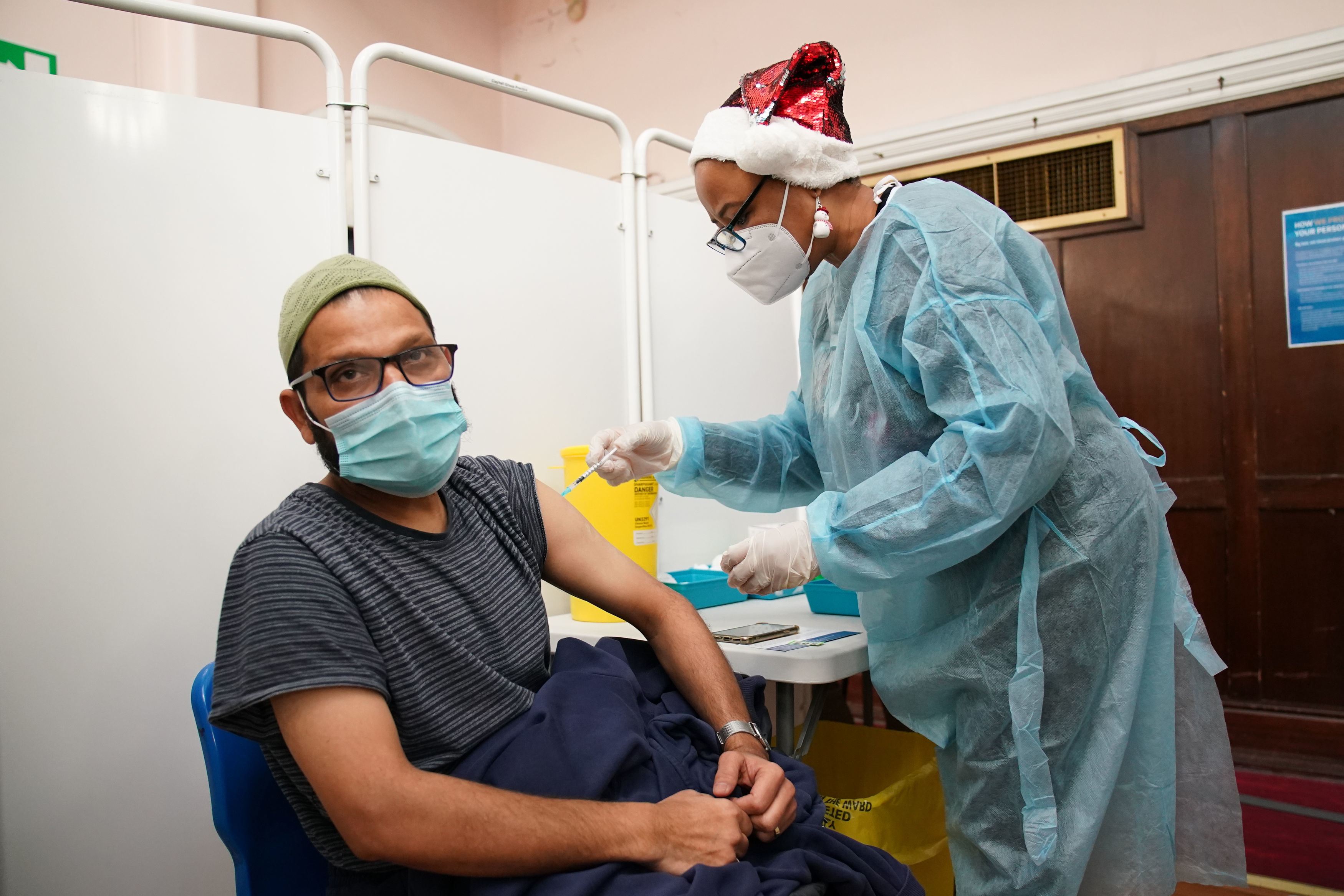 A man receives a 'Jingle Jab' Covid vaccination booster injection at Redbridge Town Hall, in Ilford, Essex, as the coronavirus booster programme continues across the UK on Christmas day. Picture date: Saturday December 25, 2021. 