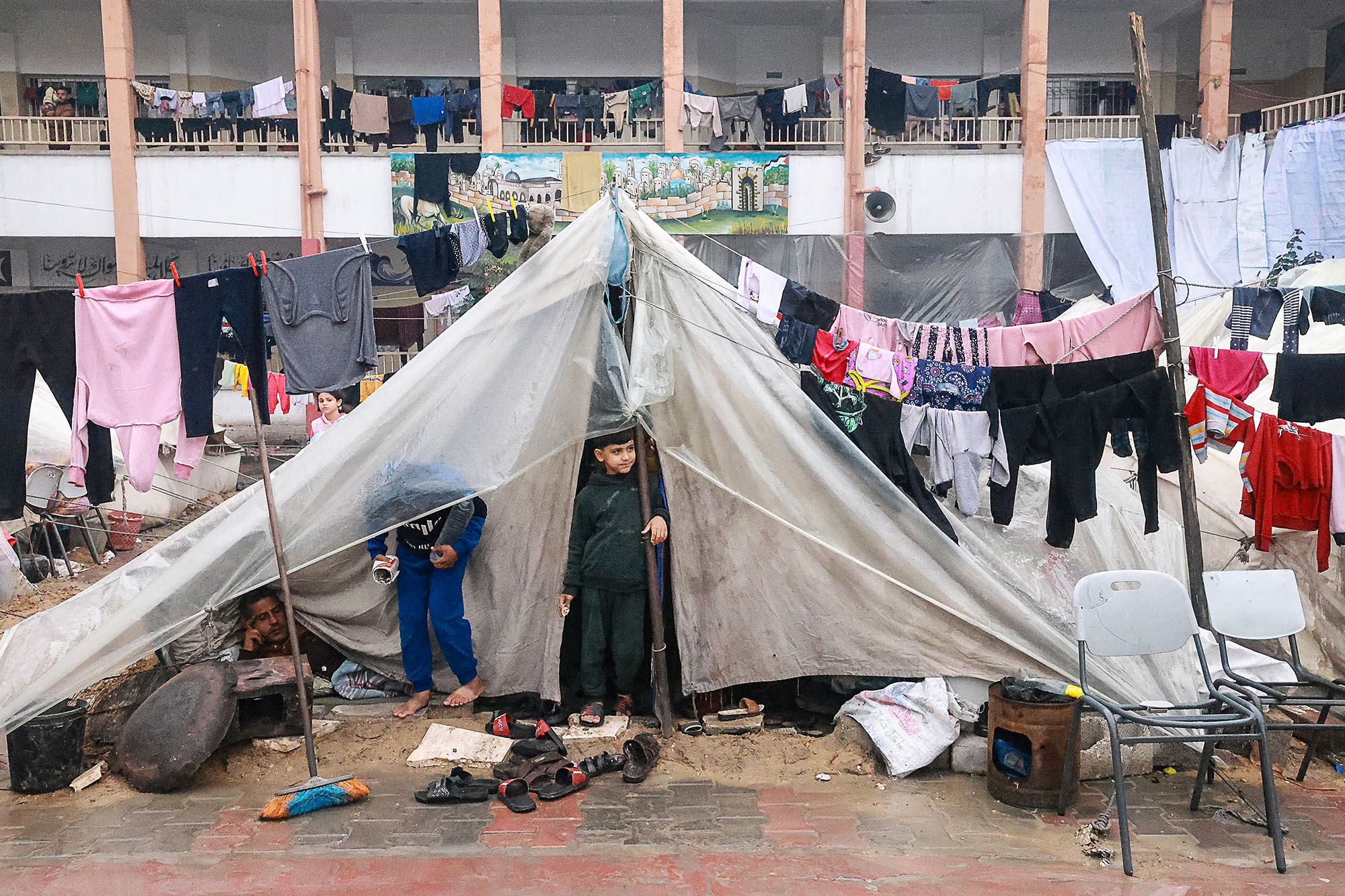 Palestinian boys stand in their makeshift tent at a camp set up on a schoolyard in Rafah, Gaza, on December 13.