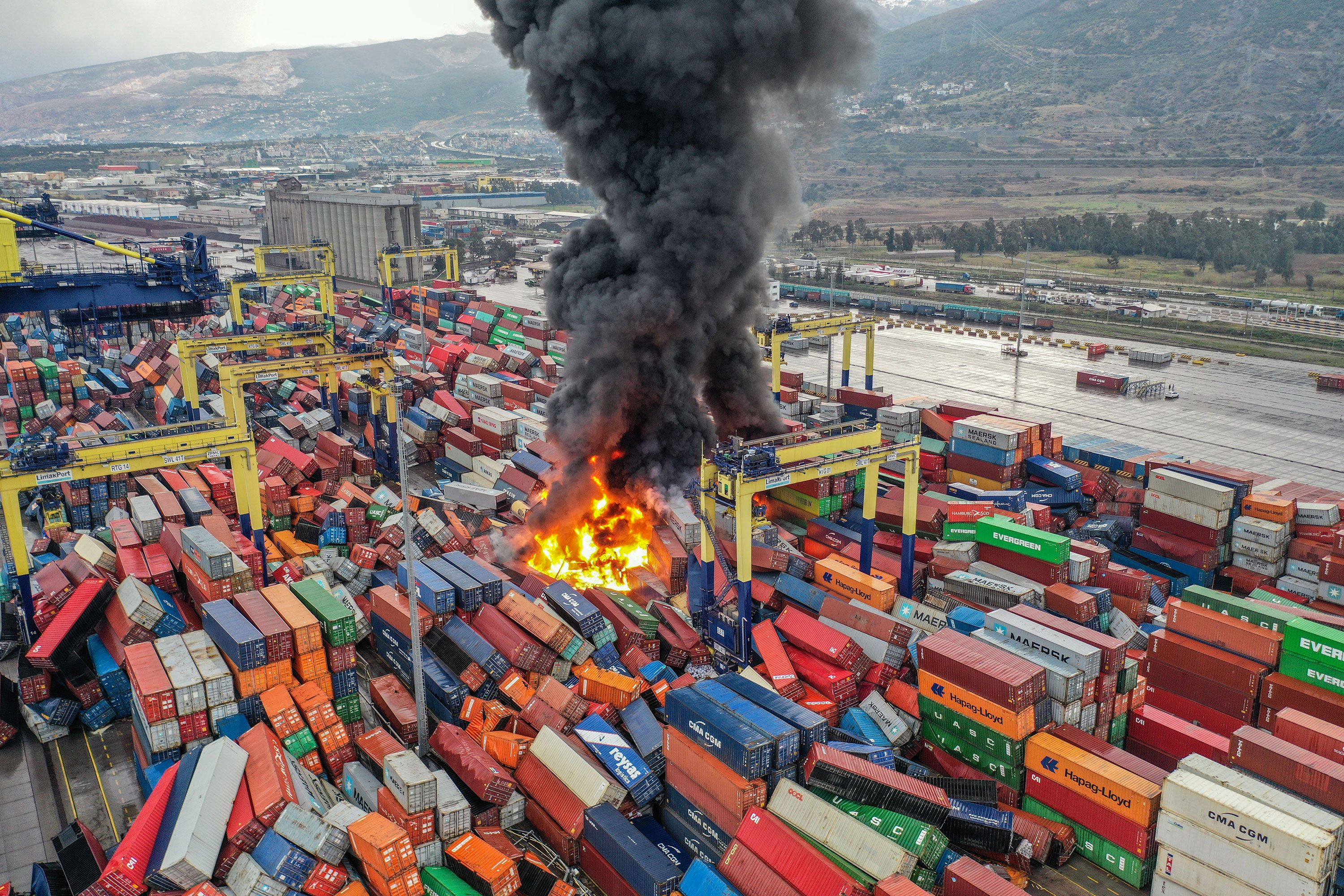 The fire burns among flipped-over containers on Monday morning, hours after the earthquake struck.