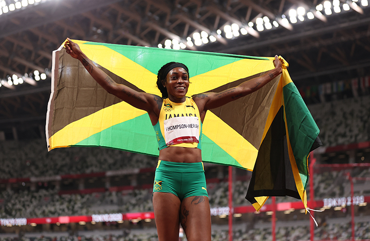 Elaine Thompson-Herah of Team Jamaica celebrates with her country's flag after winning the gold medal in the Women's 200m Final on day eleven of the Tokyo 2020 Olympic Games at Olympic Stadium on August 3, 2021.