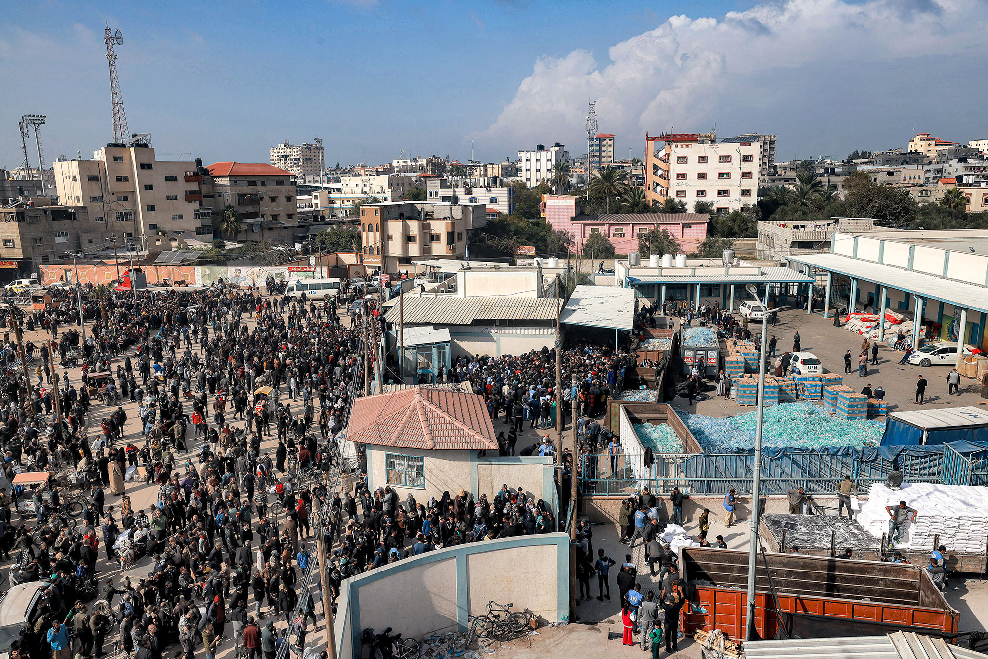 Palestinians gather gather to receive flour rations outside a warehouse of the United Nations Relief and Works Agency for Palestine Refugees (UNRWA) in Rafah, Gaza, on December 12.