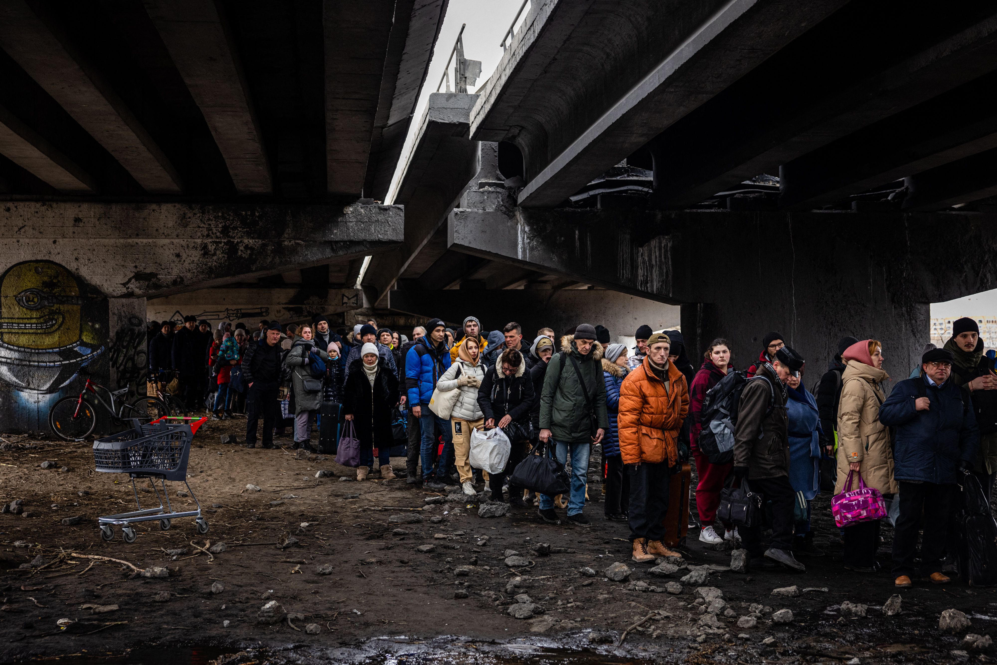 Evacuees stand under a destroyed bridge as they flee the city of Irpin, northwest of Kyiv, on March 7.