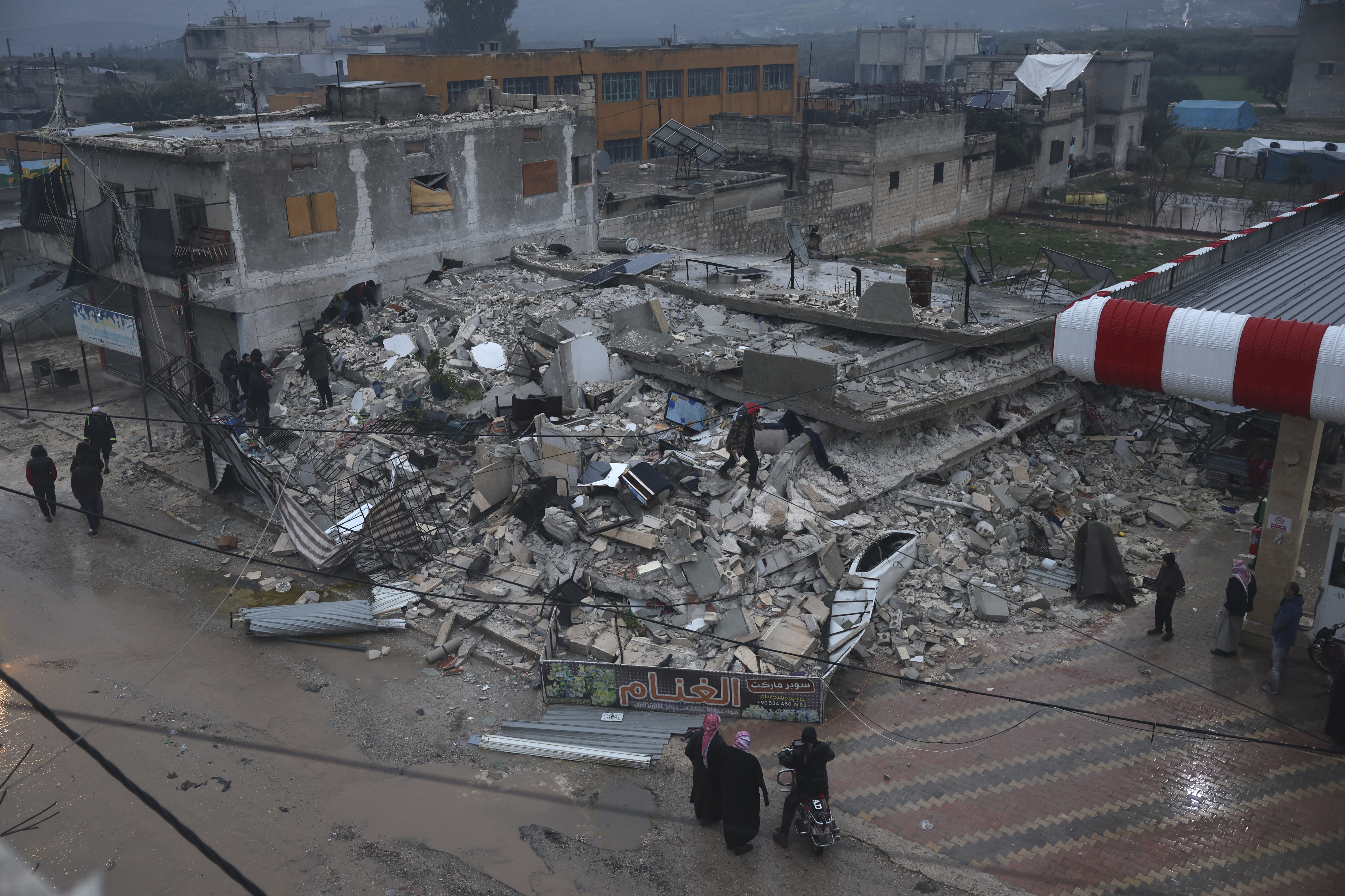 6 फरवरी को सीरिया में आए भूकंप के बाद लोग एक ढही हुई इमारत की तलाशी लेते हुए।