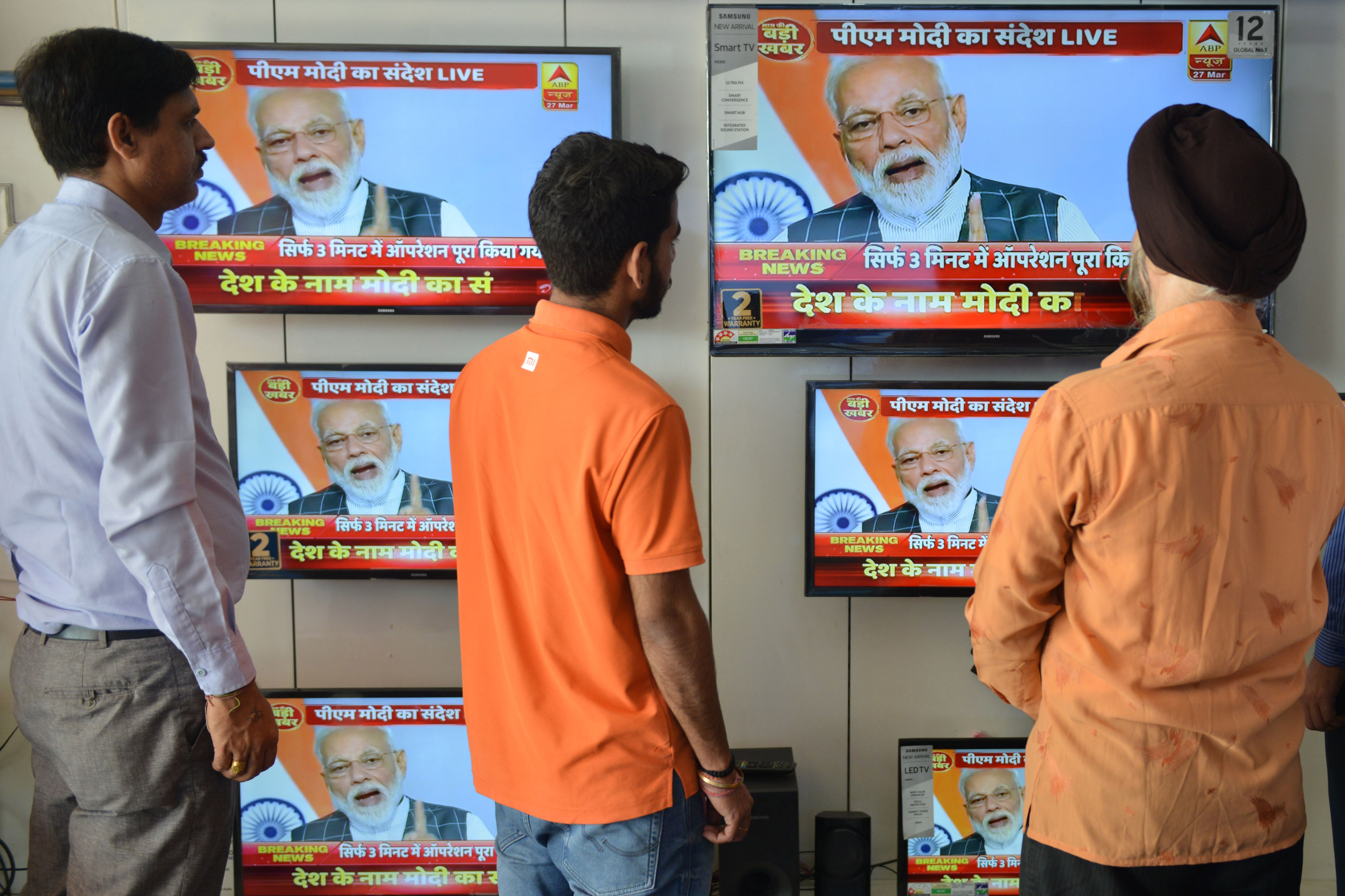 Indian men watch the live broadcast of Indian Prime Minister Narendra Modi address to the nation on televisions displayed in an electronic store, in Amritsar on March 27, 2019. 
