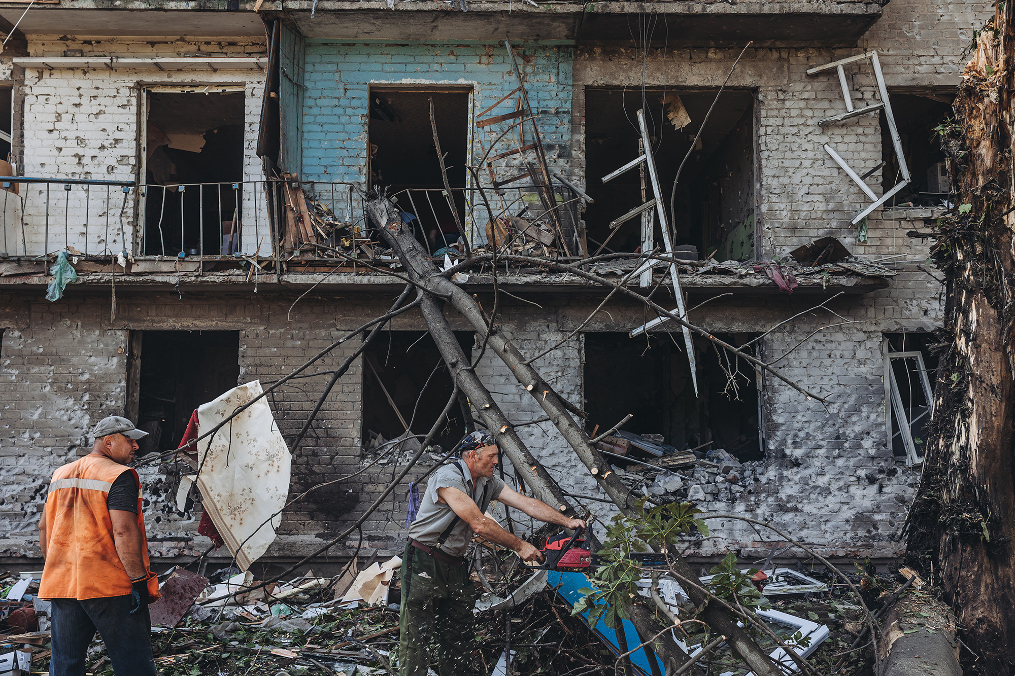 Workers cut down a tree that has fallen due to shelling in Bakhmut, Ukraine, on July 27.