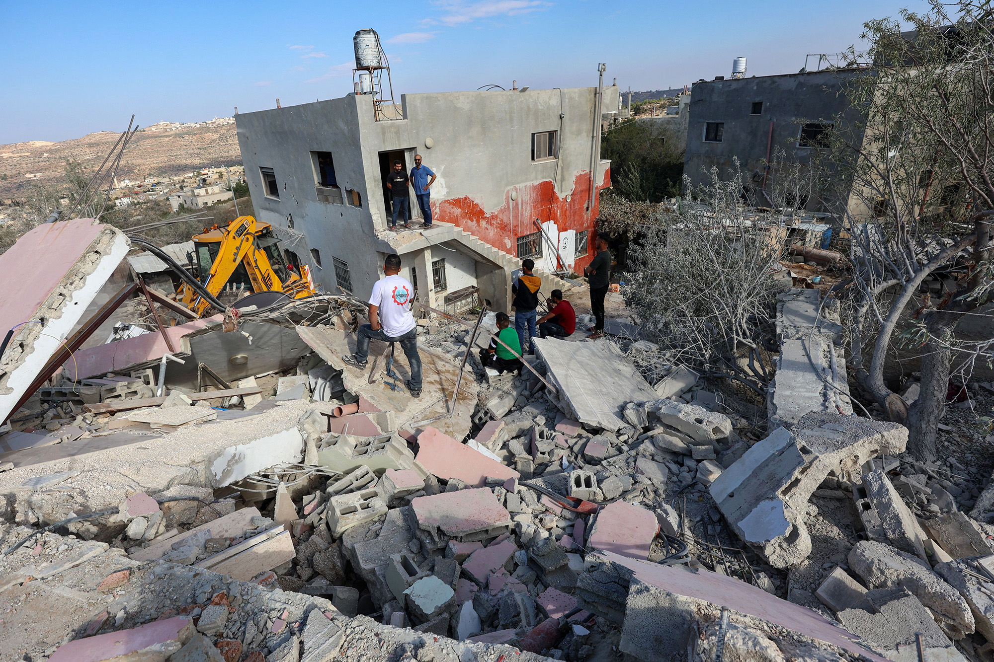 Palestinians look on as an excavator clears the rubble of the house of the deputy chief of Hamas' politcal bureau Saleh al-Aruri after it was demolished by Israeli forces in Arura village in the occupied West Bank on October 31.