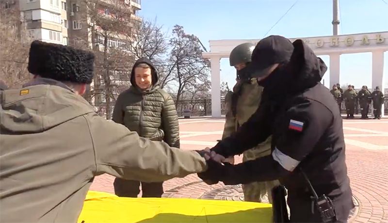 在国旗上的视频中可以看到俄罗斯军队和武装人员，“来自俄罗斯联邦国防部......俄罗斯国民警卫队......人民民兵......哥萨克人。”