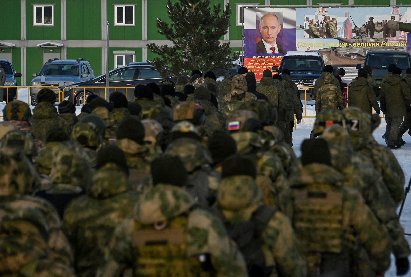 Russian reservists recruited during a partial mobilization of troops — aimed to support the country's military campaign in Ukraine — walk toward a banner with a portrait of Russian President Vladimir Putin during a ceremony before their departure in Omsk, Russia, on January 6.