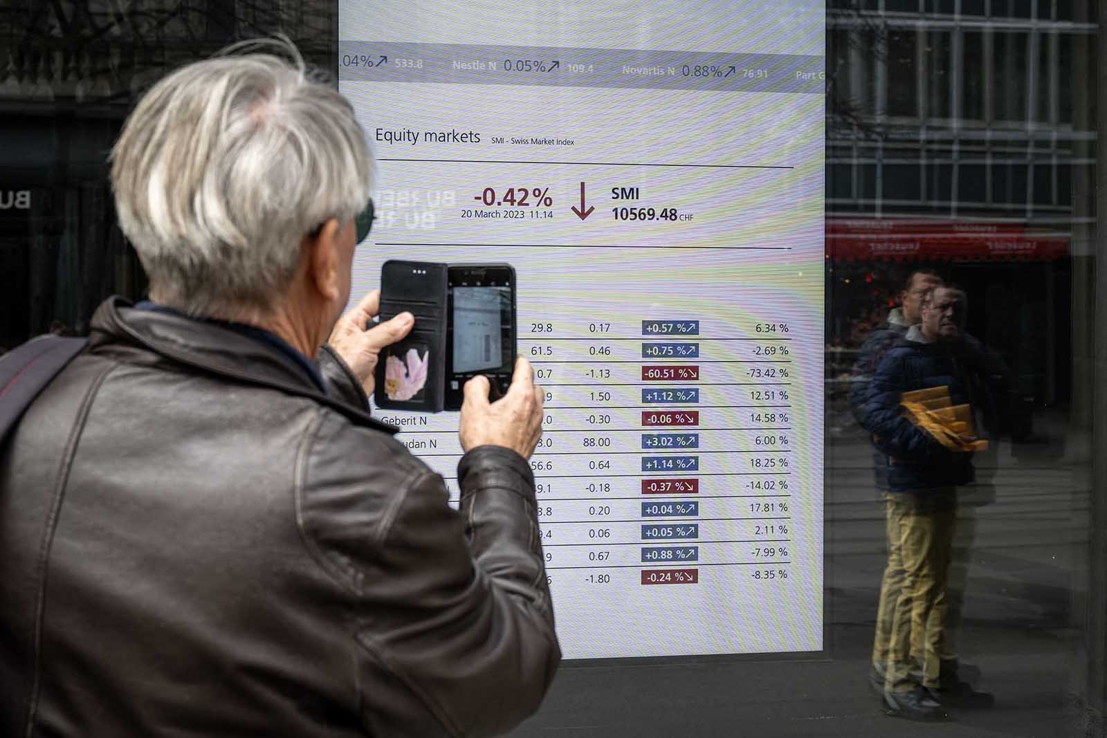 A man takes a picture with his mobile phone of a market board at the headquarters of Swiss giant banking UBS in Zurich on March 20.