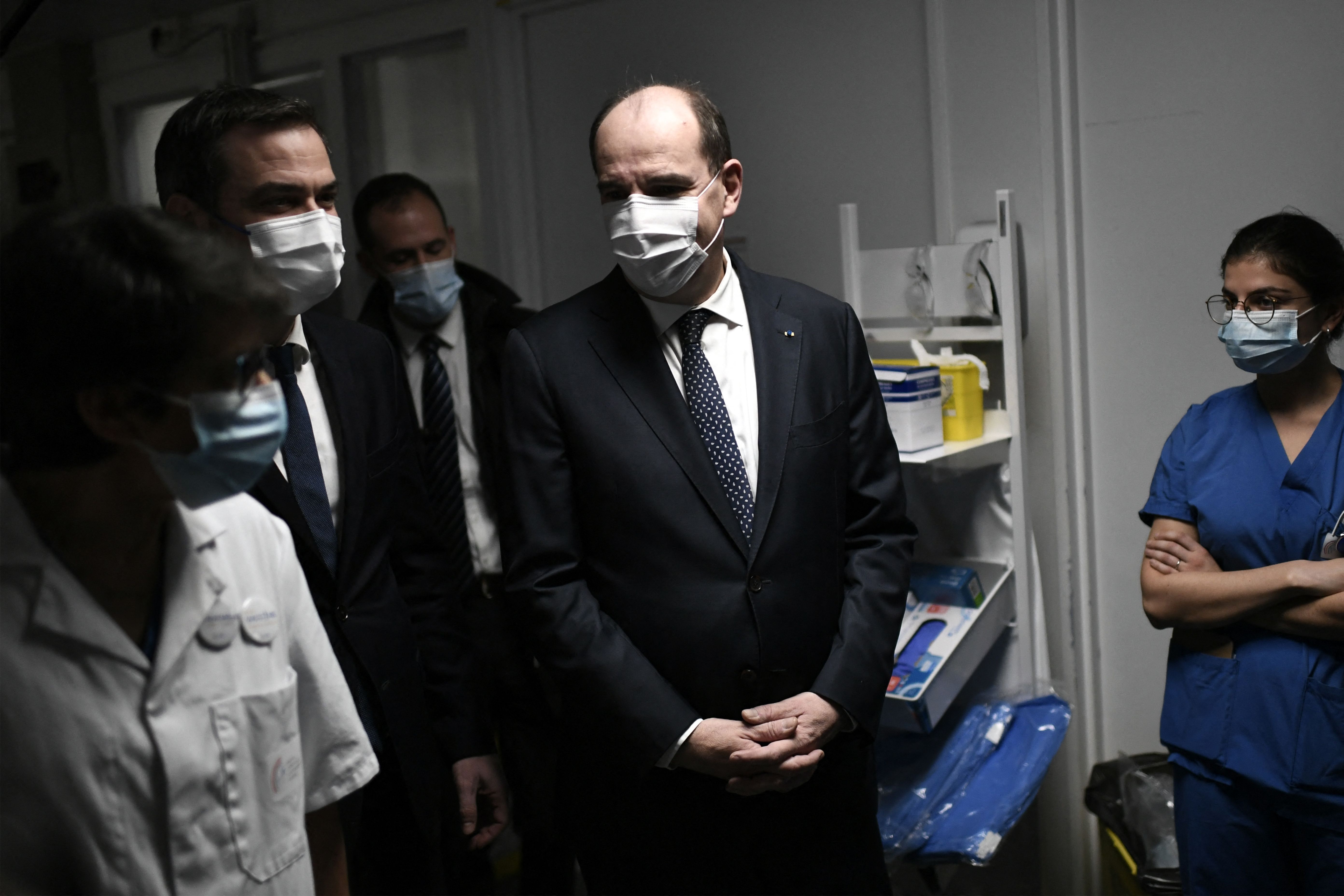 France's Prime Minister Jean Castex (C) and France's Health Minister Olivier Veran (L) speak with health workers as they visit the resuscitation unit of the Intercommunal hospital of Creteil, outside Paris, on December 28, 2021. - France reported on December 25 over 100,000 daily Covid cases, a record since the pandemic erupted nearly two years ago, with many experts warning the number would rapidly increase over the coming weeks. 
