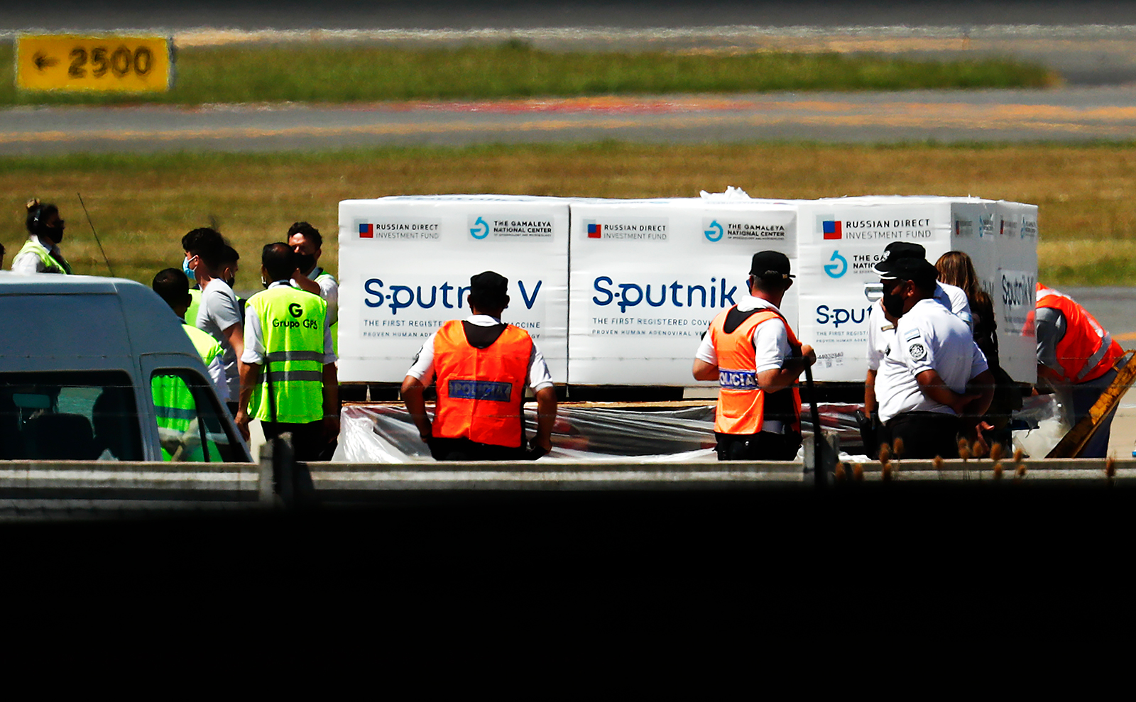 Los funcionarios del aeropuerto están manejando contenedores con unas 300.000 dosis del primer lote de la vacuna Sputnik V de Rusia mientras los agentes de policía montan guardia en el Aeropuerto Internacional Ministro Pistarini en Ezeiza, Argentina, el 24 de diciembre.