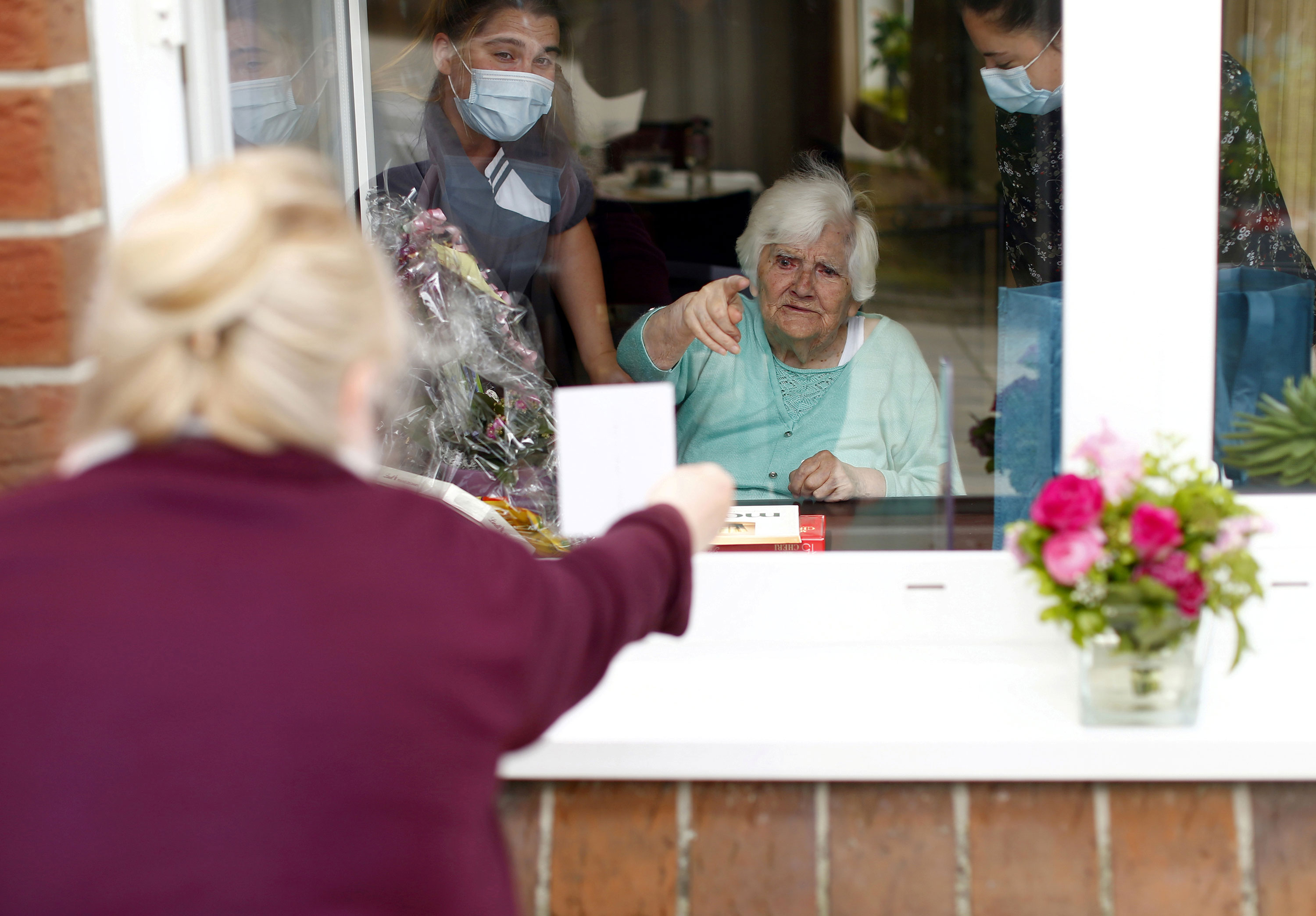 A woman shows family pictures to her mother through a window in Neuss, Germany, on Mother's Day, May 10.