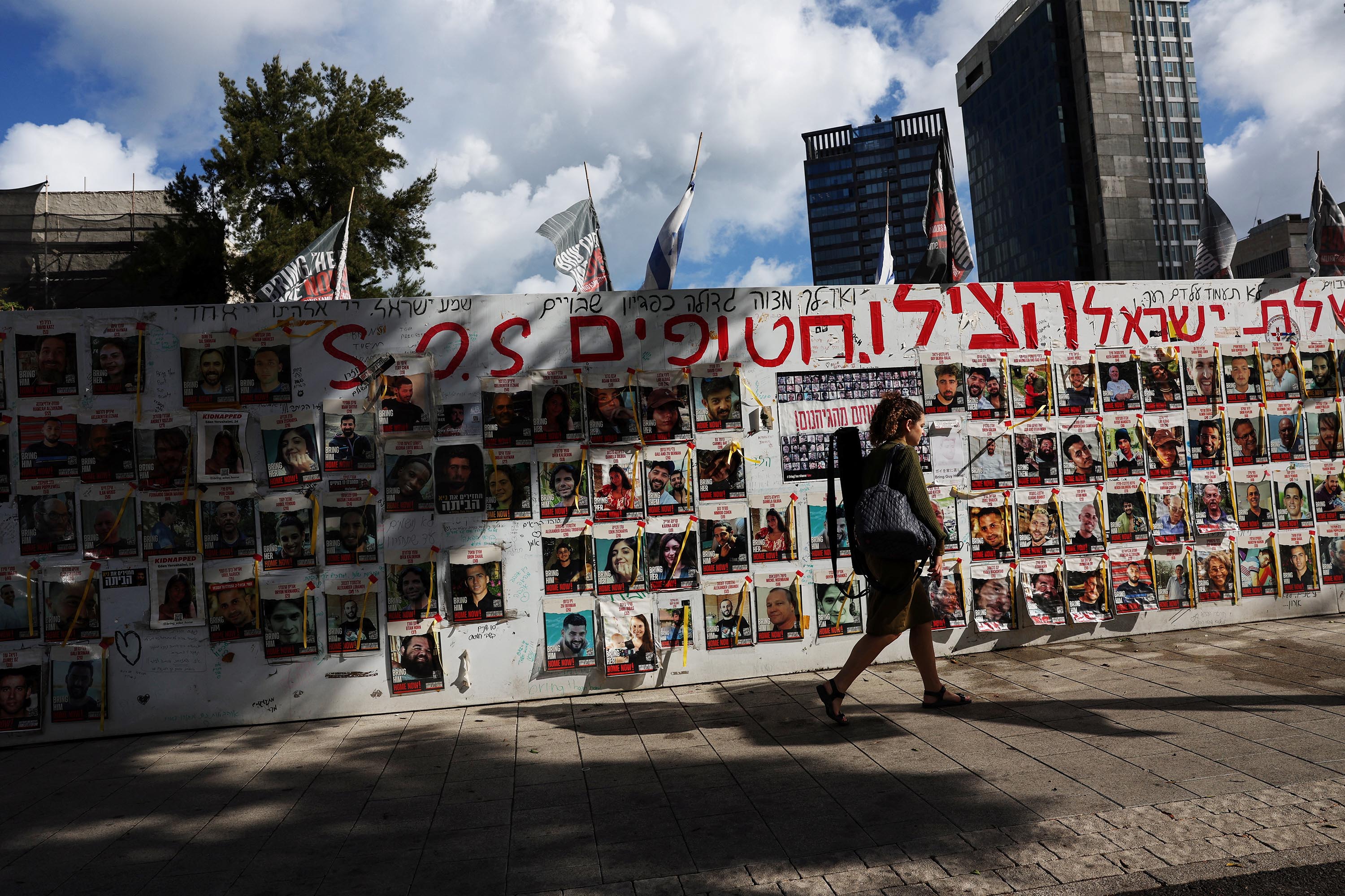 A person walks by a wall of posters of hostages kidnapped by Hamas, in Tel Aviv, Israel, on May 6. 