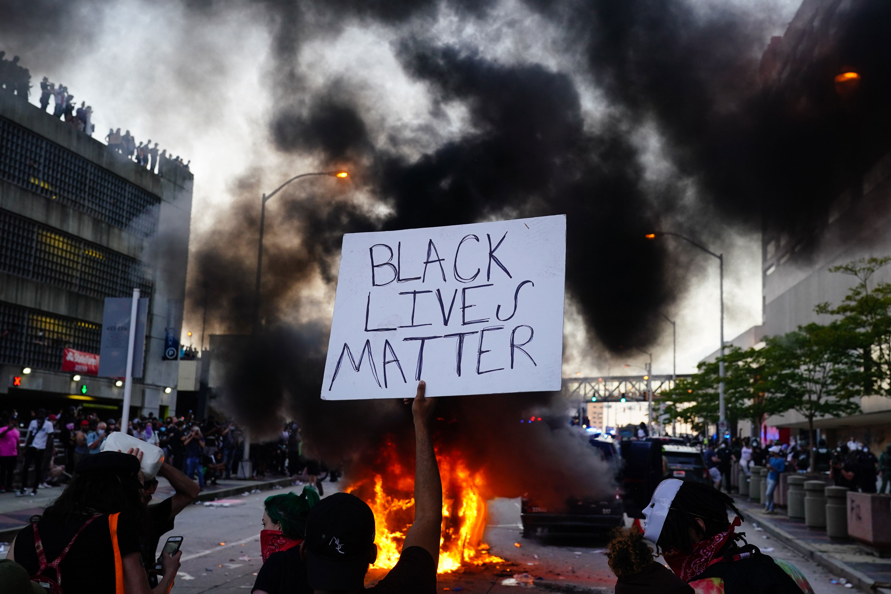 A man holds a Black Lives Matter sign as a police car burns in Atlanta on May 29.