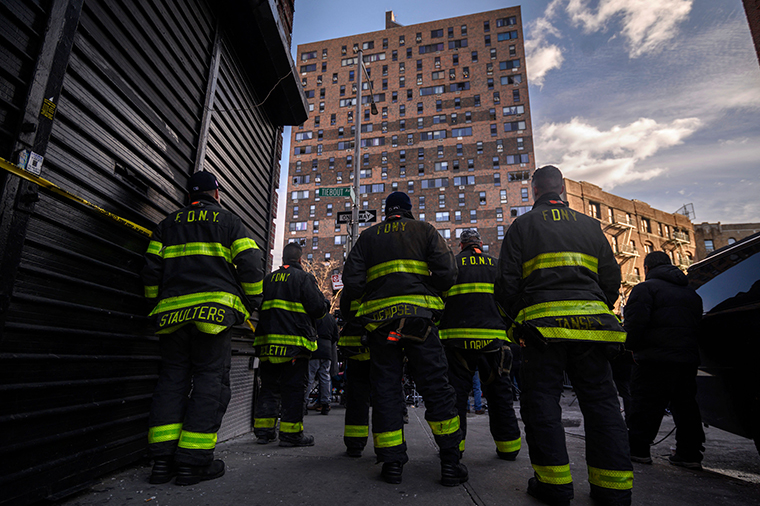 Firefighters stand outside the scene of an apartment building fire as they listen to New York City Fire Commissioner Daniel Nigro speak to reporters in the Bronx, New York on January 10.