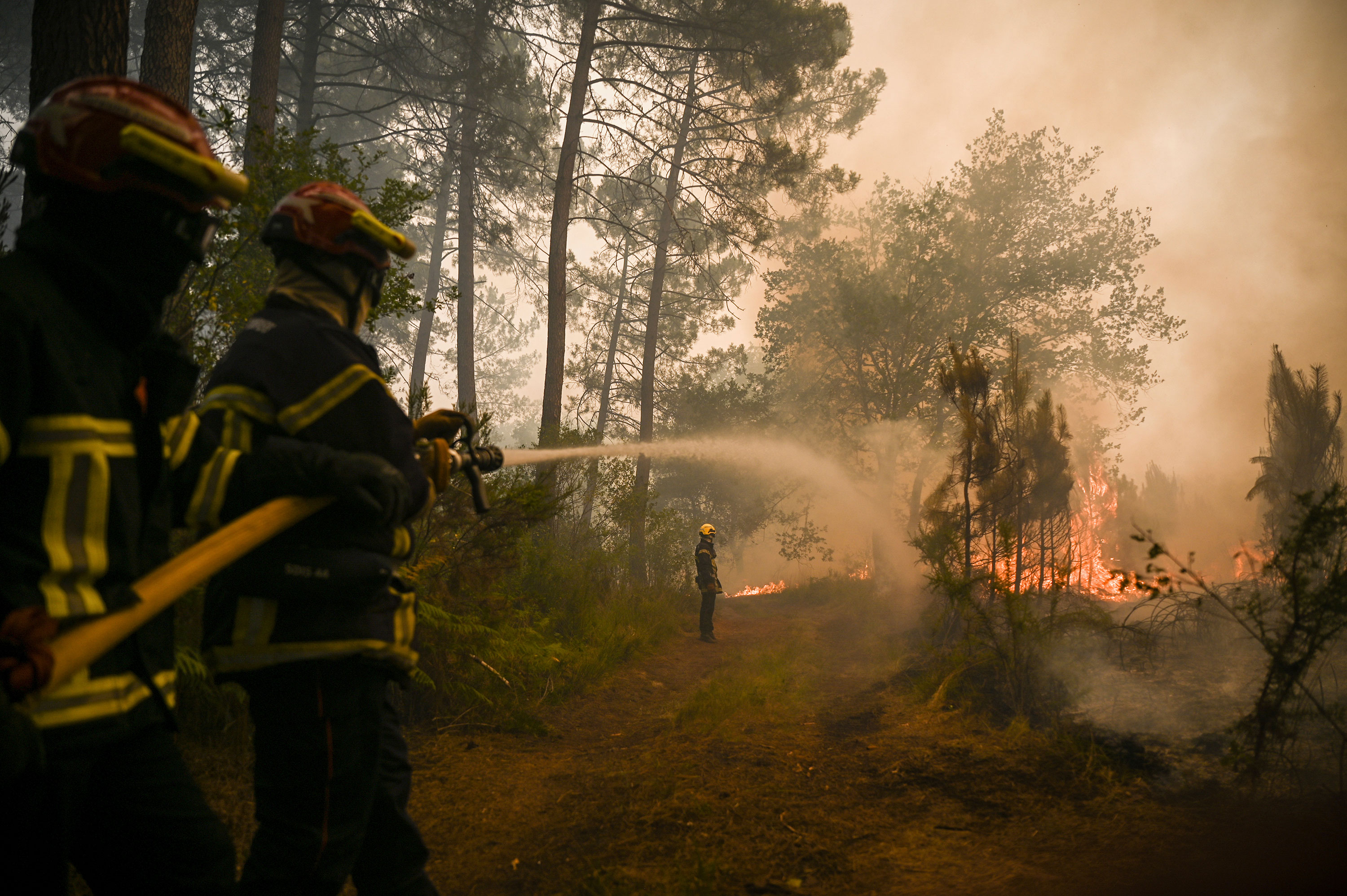 Firefighters douse flames near Louchats, France, on July 18.