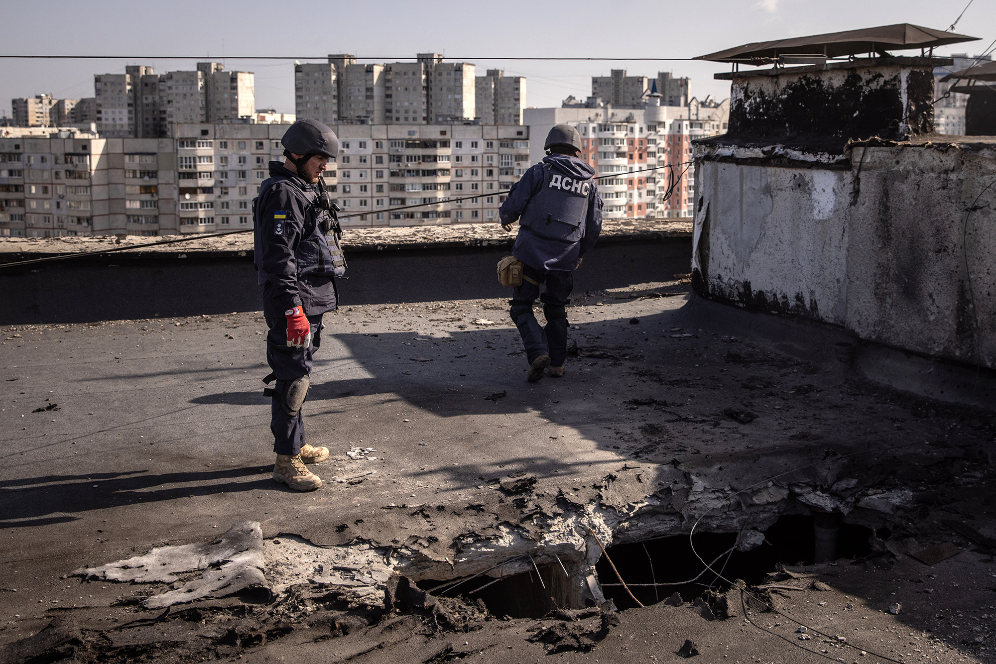 Members of the Kharkiv emergency response services unit search a rooftop for rocket debris from recent Russian attacks on April 15, in Kharkiv, Ukraine. 