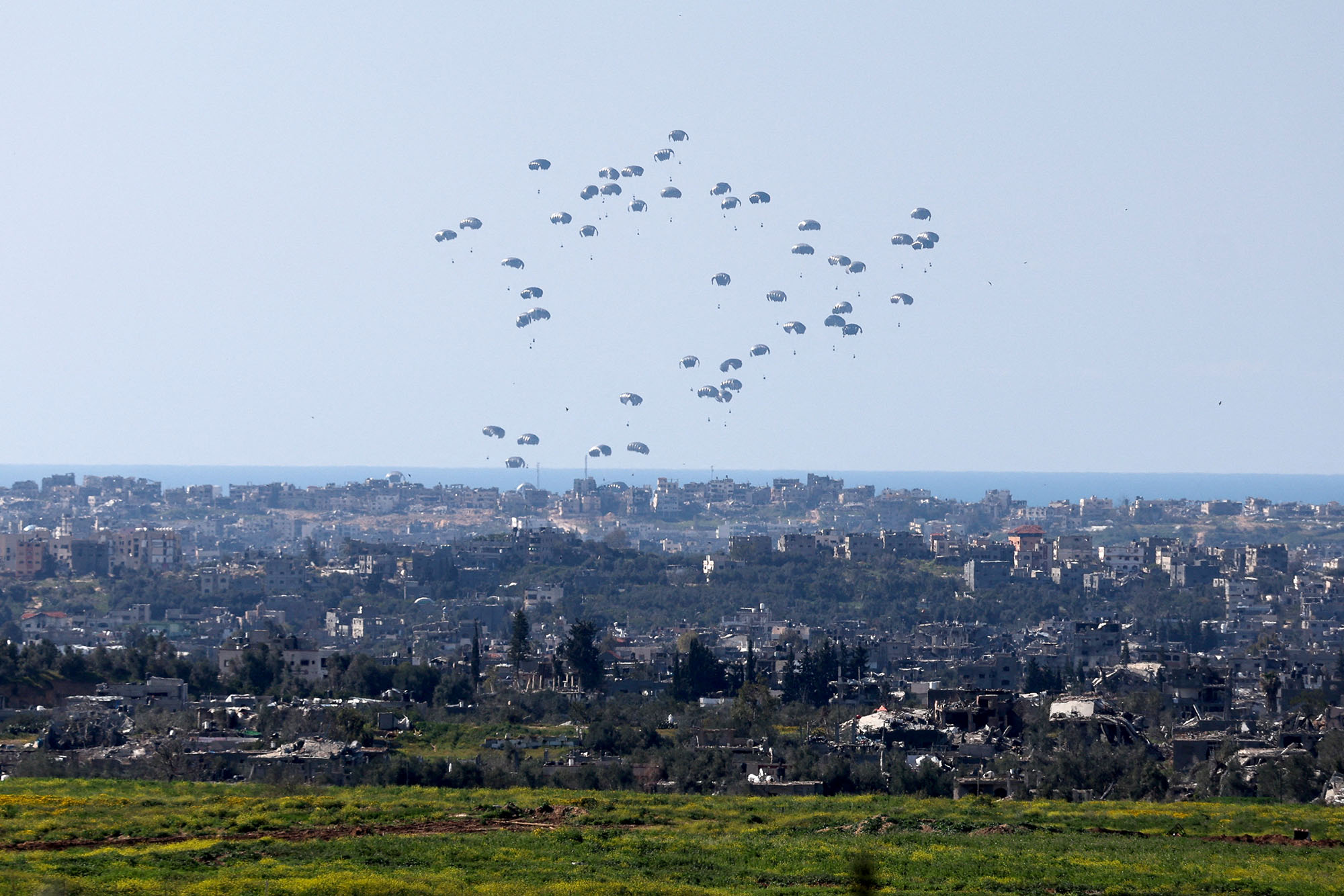Packages fall towards northern Gaza after being dropped from a military aircraft, as seen from Israel's border with Gaza, in southern Israel, on March 11.