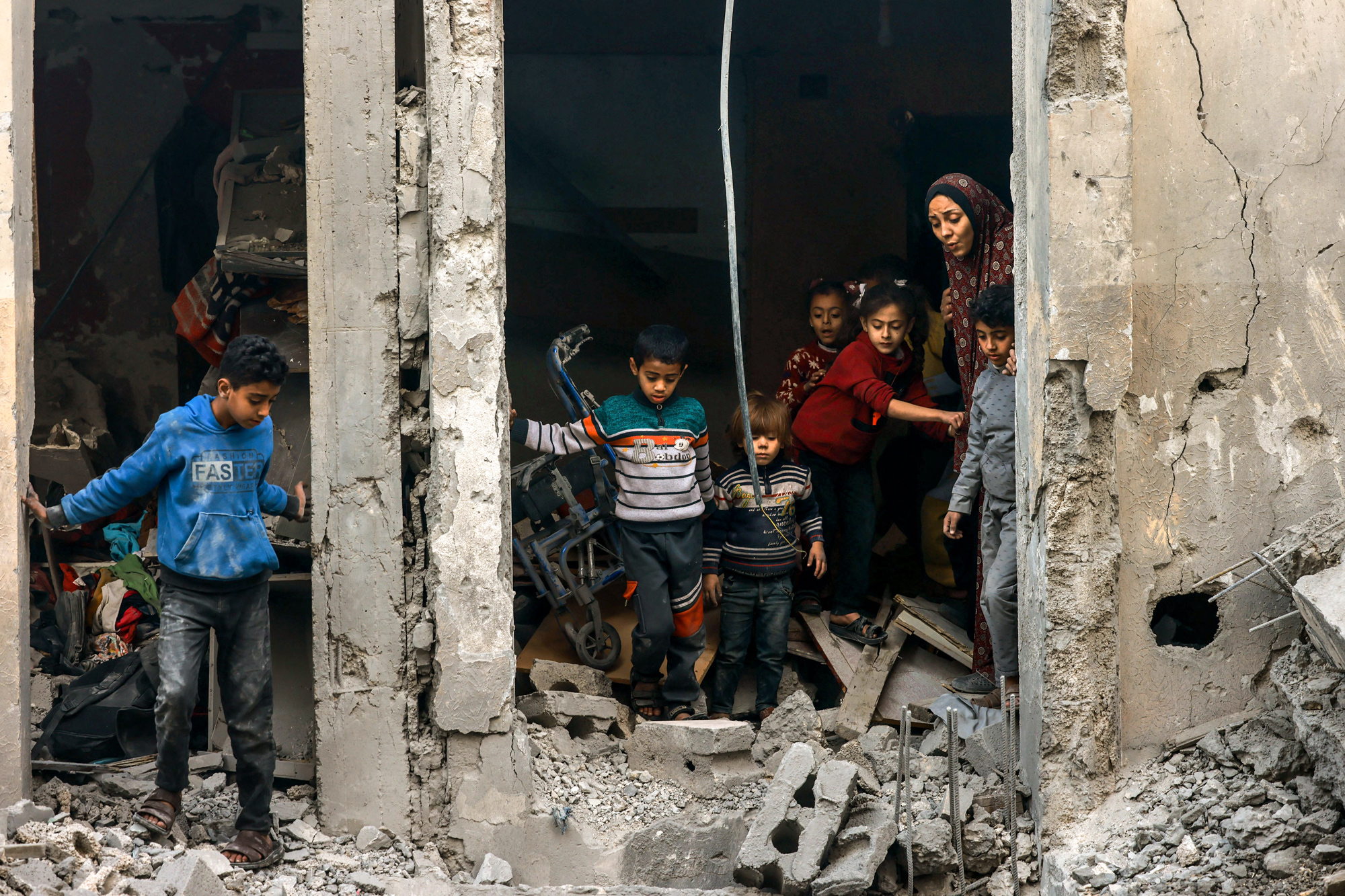 A Palestinian woman and children check debris following Israeli bombardment in Rafah, southern Gaza, on December 22, 2023.