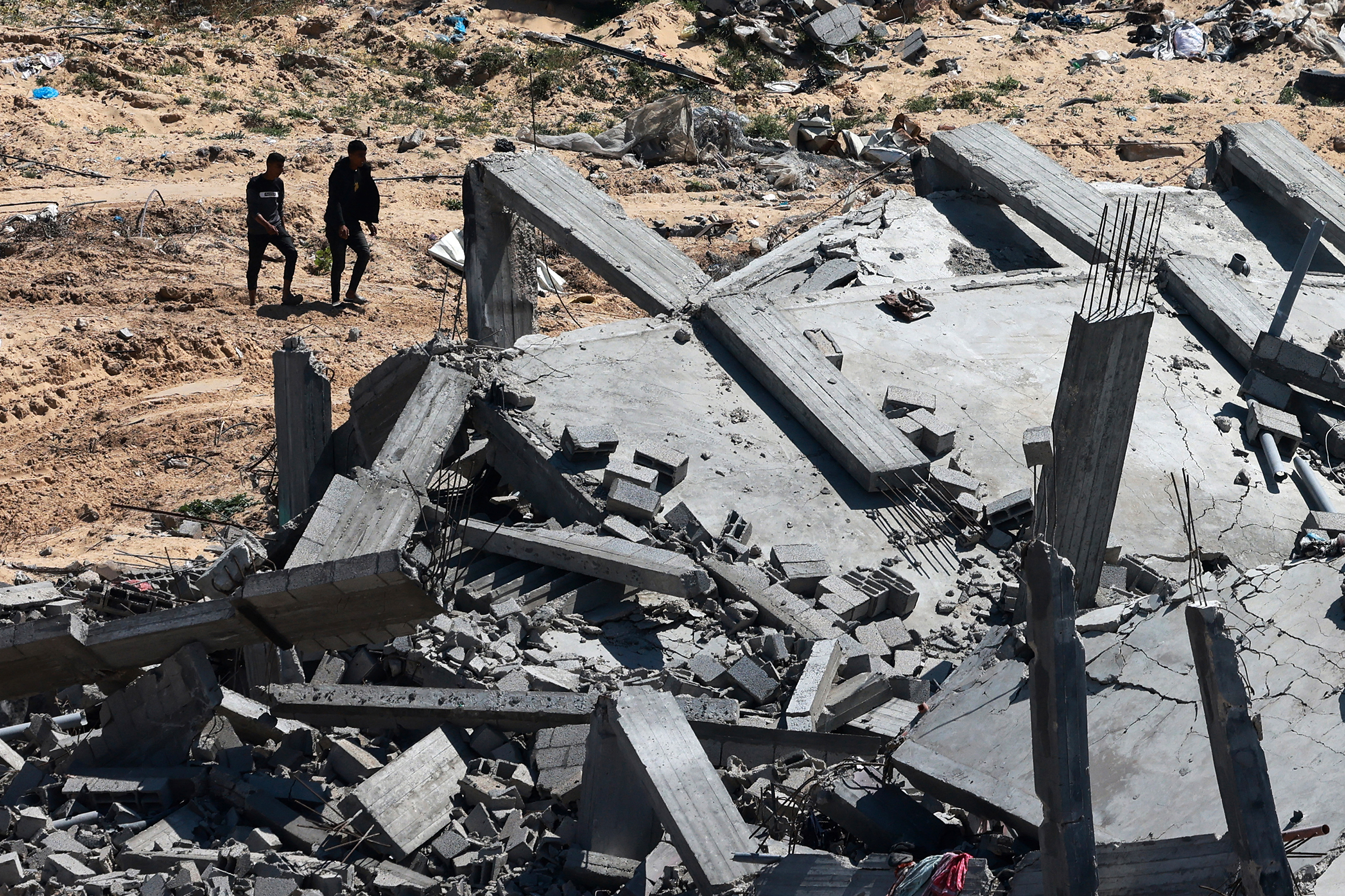 Men walk past a destroyed building in Khan Younis, Gaza, on April 7. 