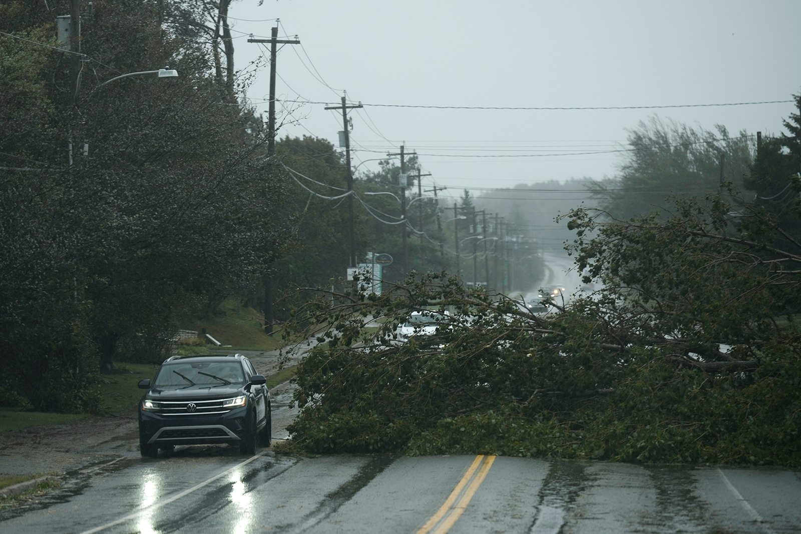 Vehicles navigate around a downed tree on Saturday, Sept. 24, in East Bay, Nova Scotia, on Cape Breton Island in Canada.