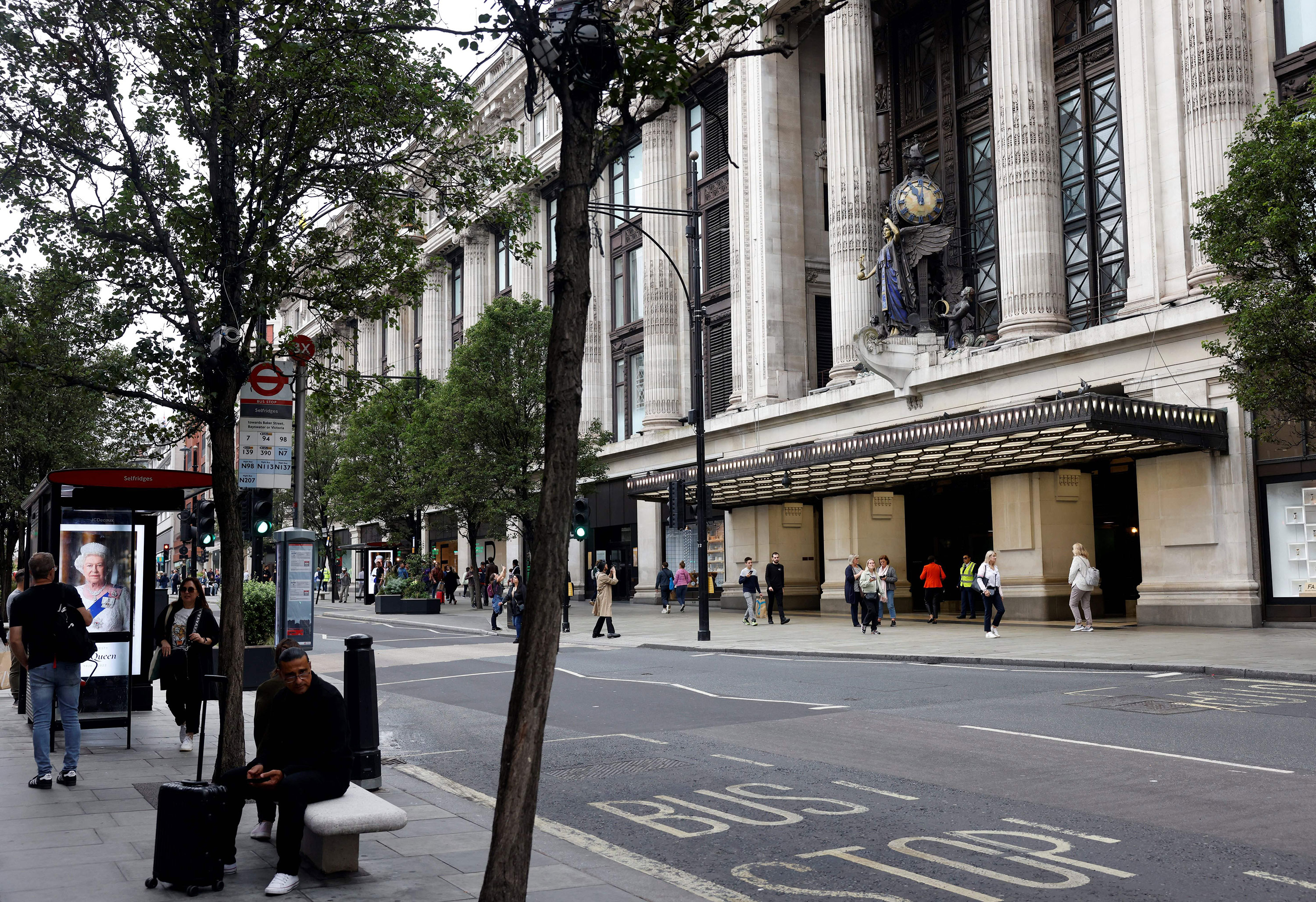 People walk past closed shops, including Selfridges, on Oxford Street in London on Friday.