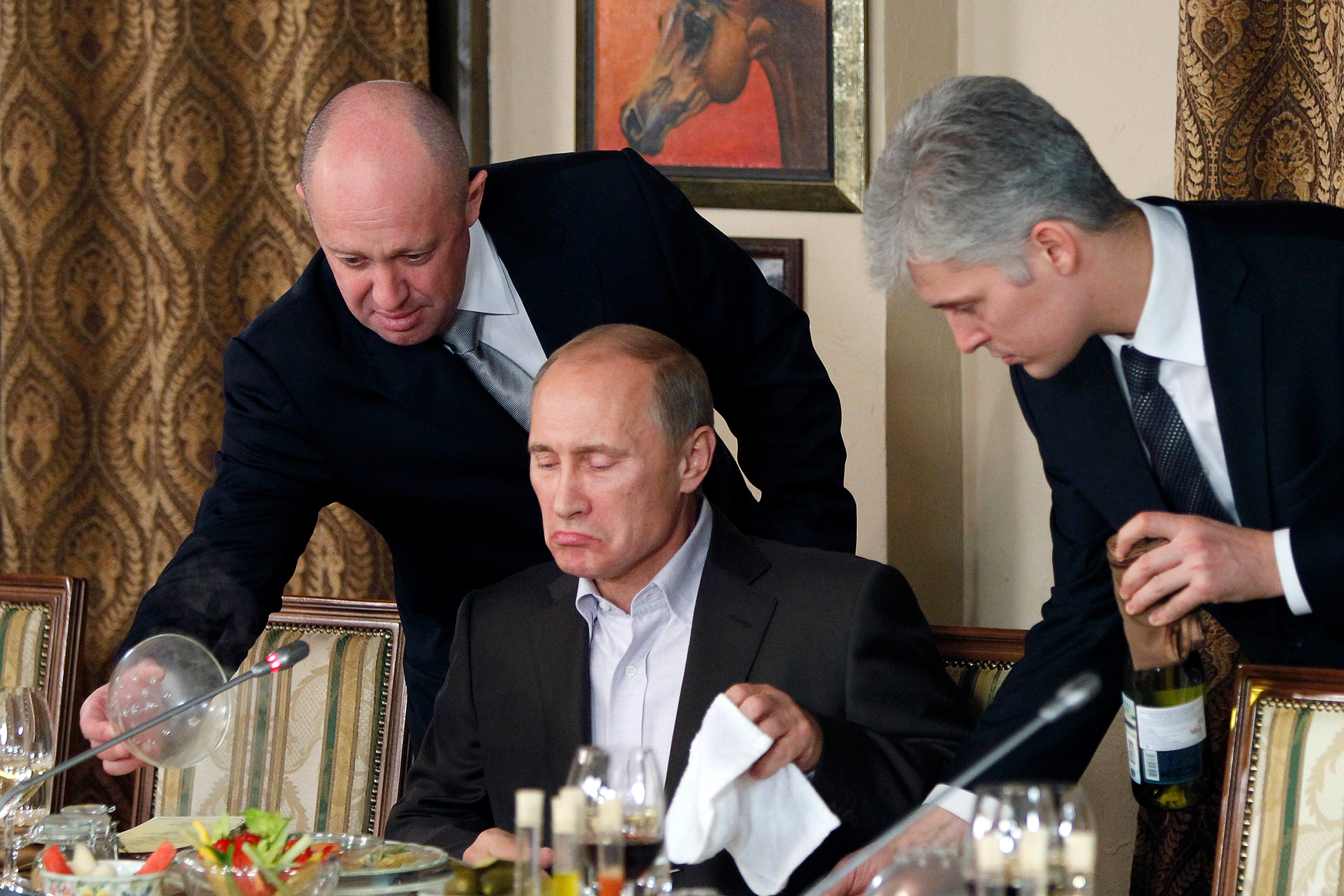 Prigozhin, left, serves food to Putin during a dinner at Prigozhin's restaurant in 2011. 