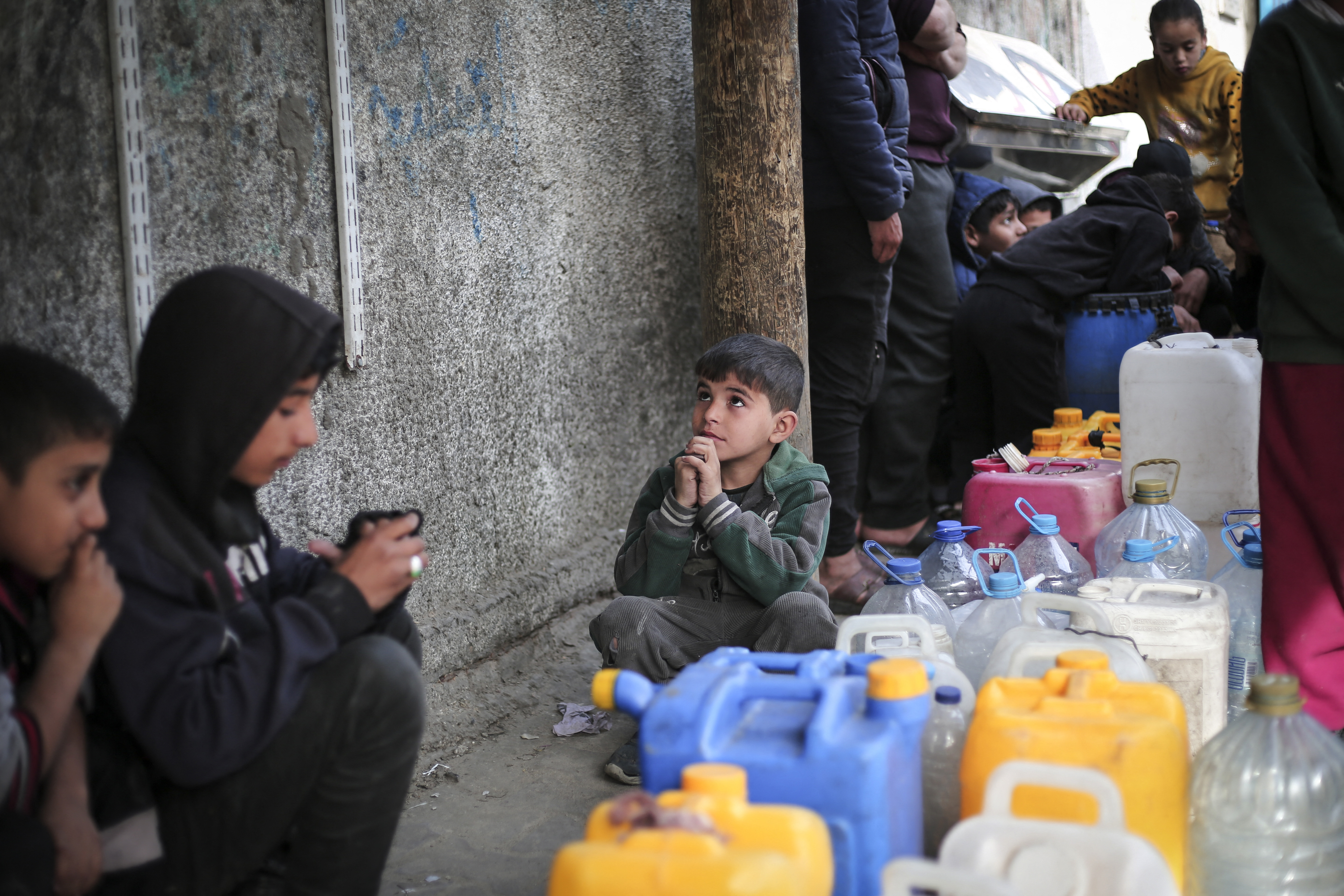 Children gather around containers of water in Rafah, Gaza, on March 1.