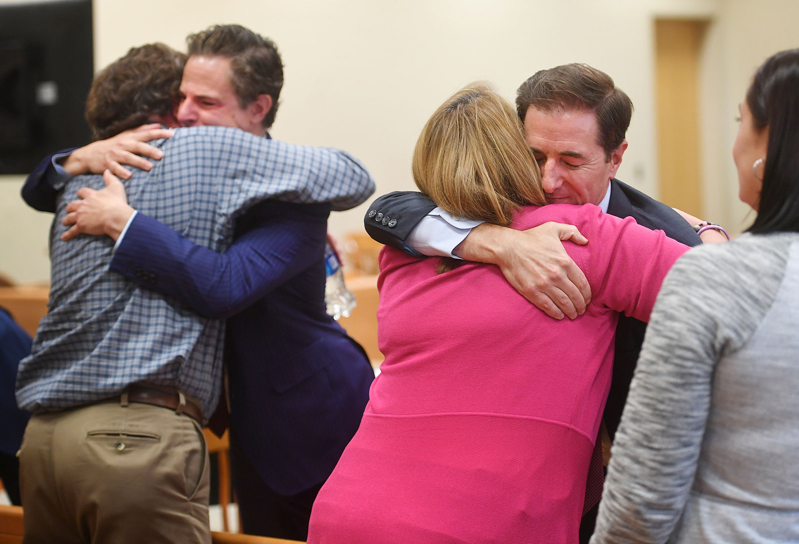 William Sherlach, left, hugs attorney Josh Koskoff while Nicole Hockley hugs attorney Chris Mattei following the jury verdict on Wednesday.