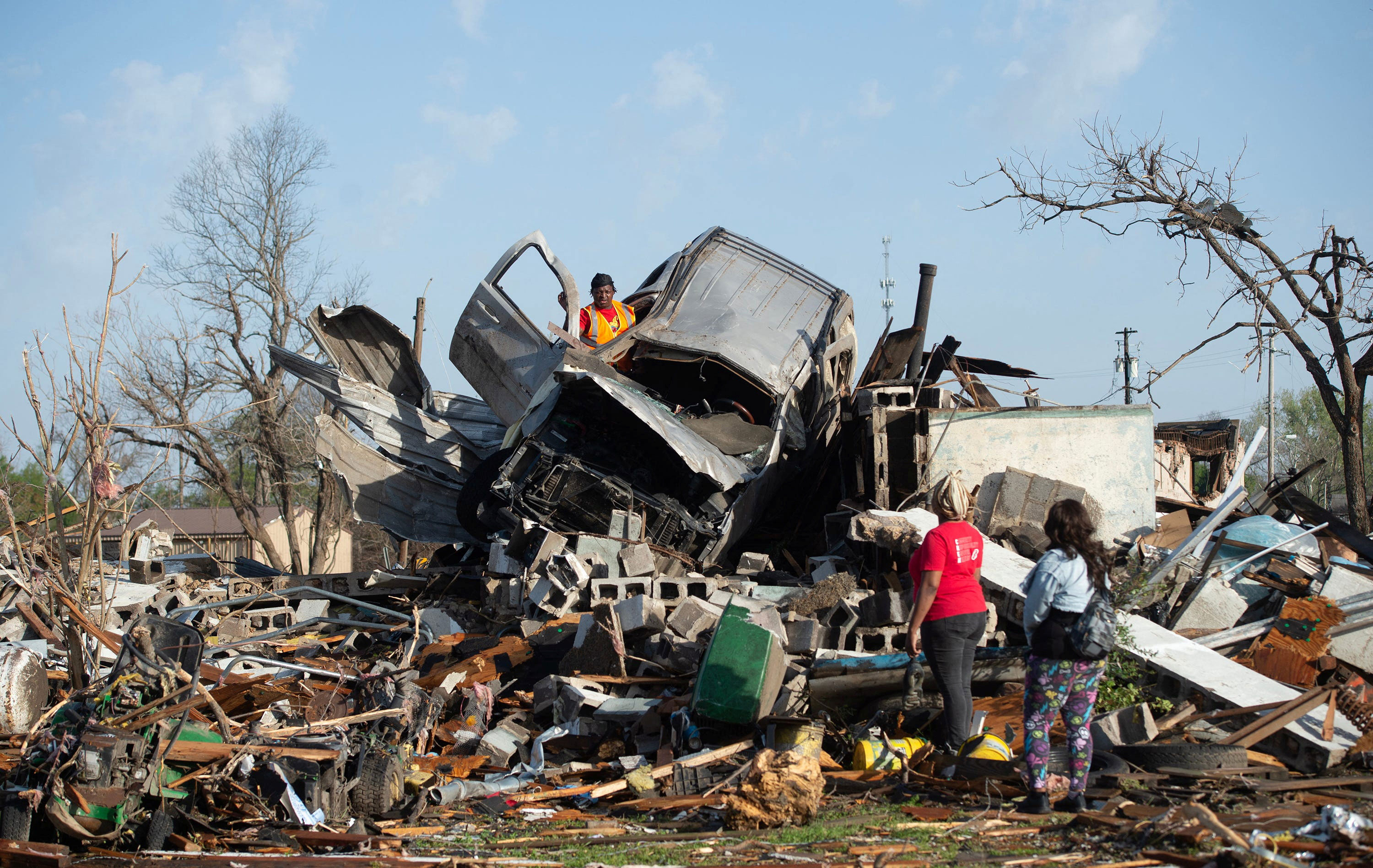 KeUntey Ousley tries to salvage what he can from his mother's boyfriend's vehicle in Rolling Fork on Saturday as his mother LaShata Ousley and his girlfriend Mikita Davis watch. 