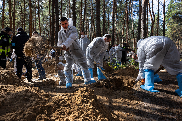 Workers and forensic police exhume bodies from unidentified makeshift graves at the Pishanske cemetery on Monday, September 19, in Izium, Ukraine. 