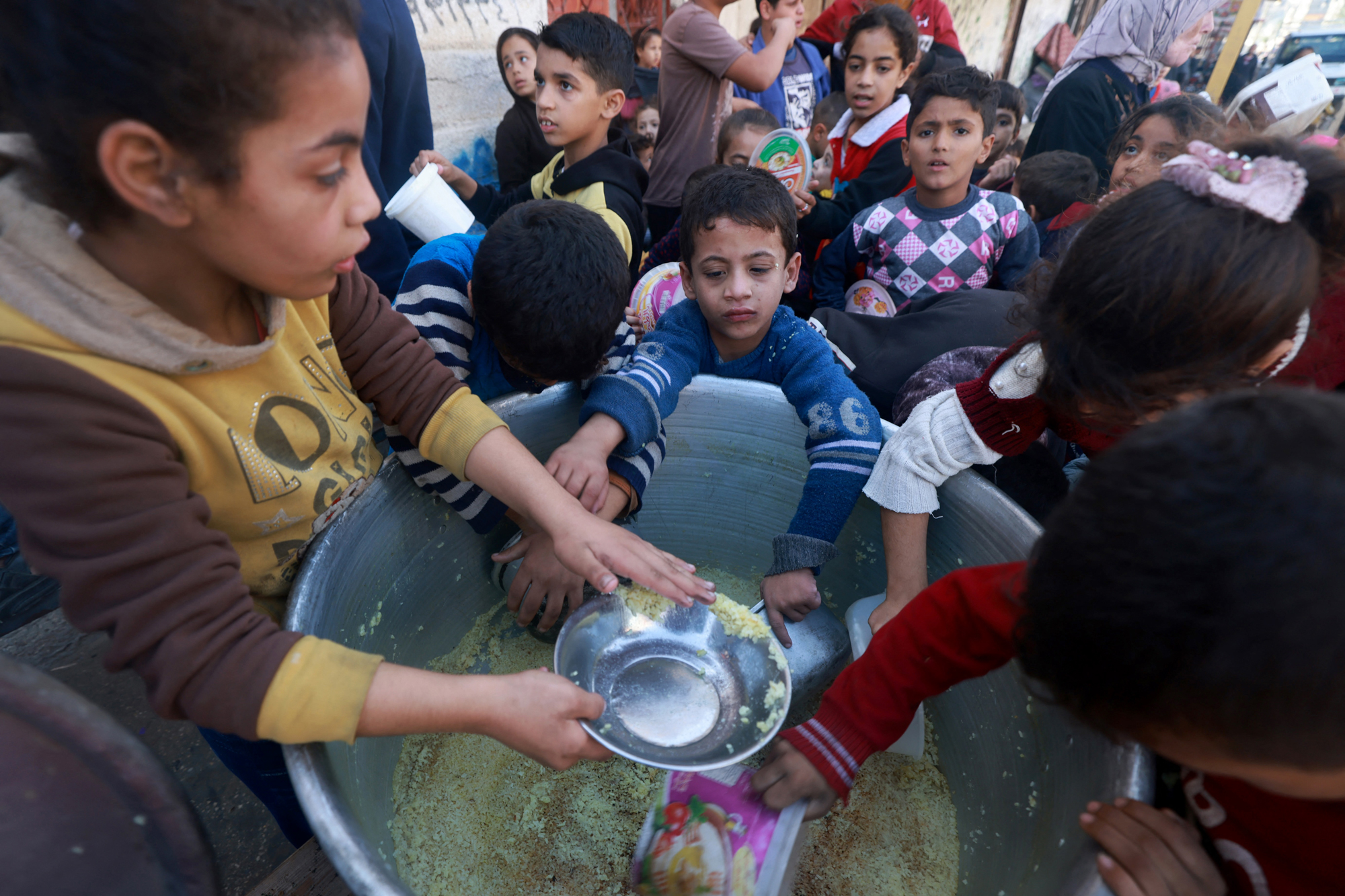 Palestinian children collect food at a donation point provided by a charity group in the southern Gaza city of Rafah, on December 6.