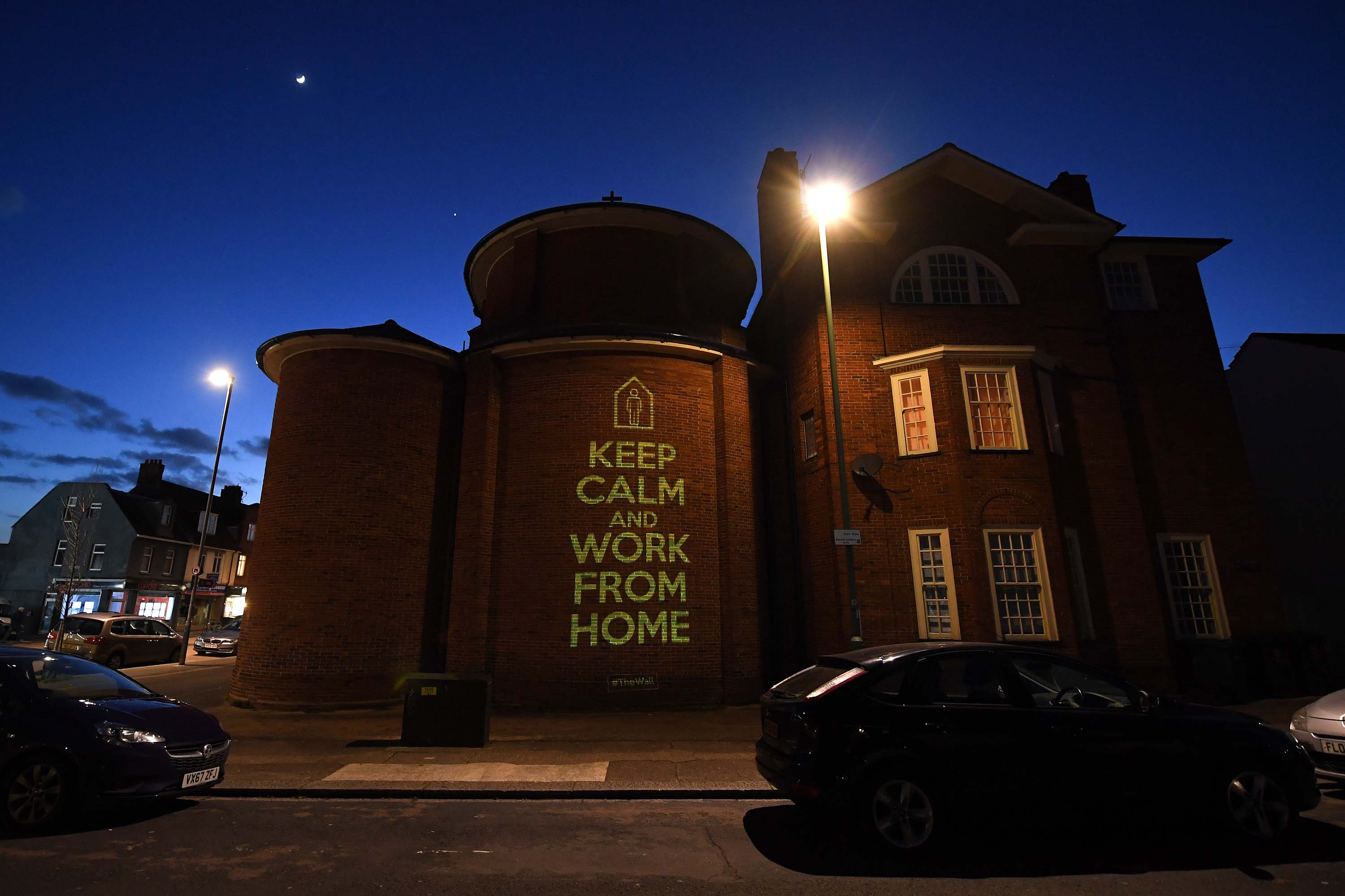 A message of 'Keep Calm And Work From Home' by artist Mike Dicks is projected onto a wall of a church in Brighton & Hove, England, on March 29.