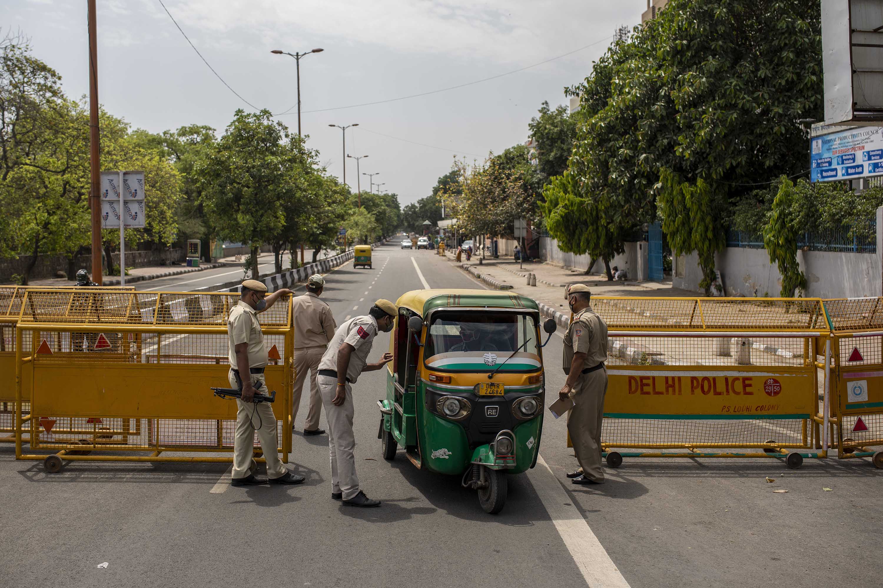Police officers stop a vehicle at a check point during a weekend lockdown in Delhi, on Saturday, April 17. 