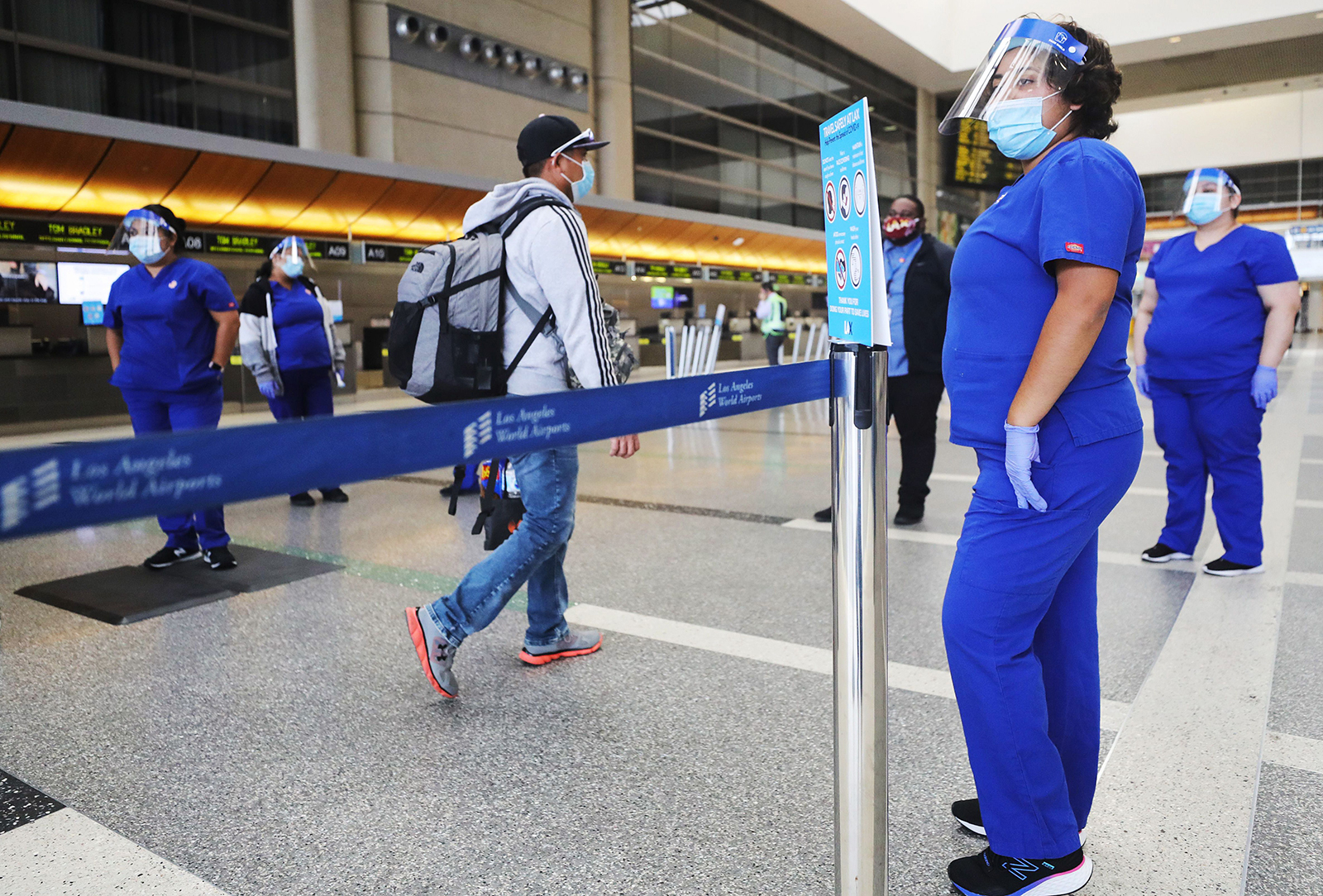 A traveler walks past screeners testing a system of thermal imaging cameras which check body temperatures at Los Angeles International Airport on June 24, in Los Angeles, California. 