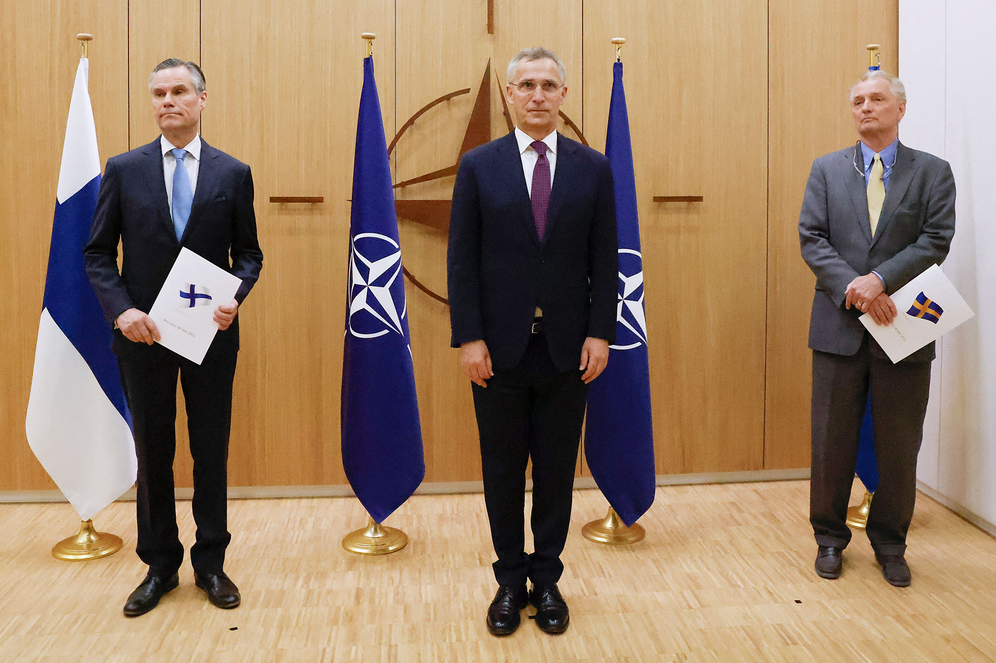 inland's Ambassador to NATO Klaus Korhonen, NATO Secretary-General Jens Stoltenberg and Sweden's Ambassador to NATO Axel Wernhoff pose during a ceremony to mark Sweden's and Finland's application for membership in Brussels, Belgium, on May 18.