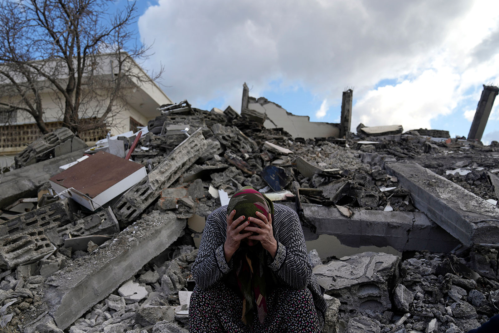 A woman sits on rubble as emergency rescue teams search for people under the remains of destroyed buildings in Osmaniye, Turkey, on Tuesday. 
