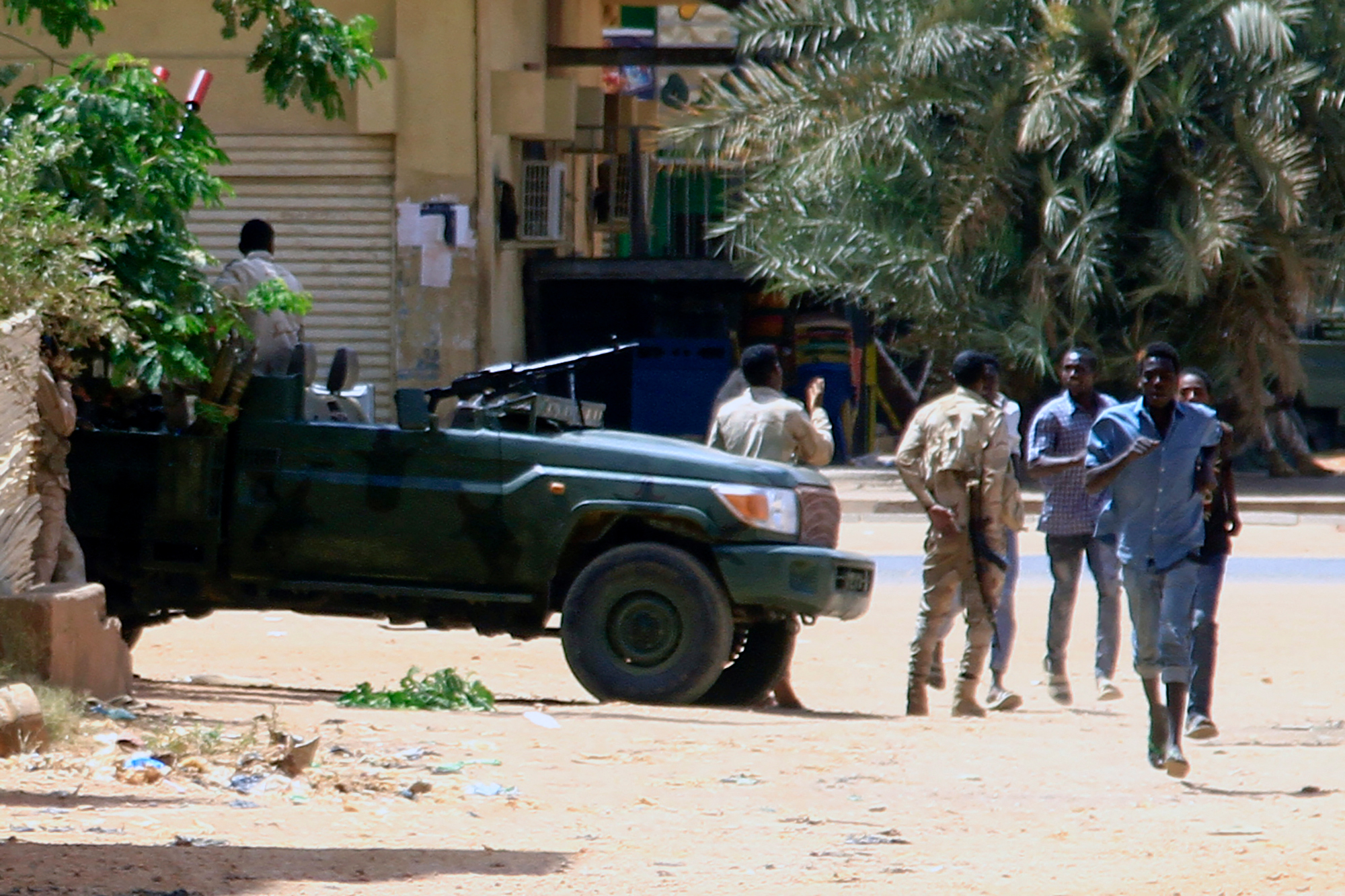 People run past a military vehicle in Khartoum, Sudan, on April 15. 