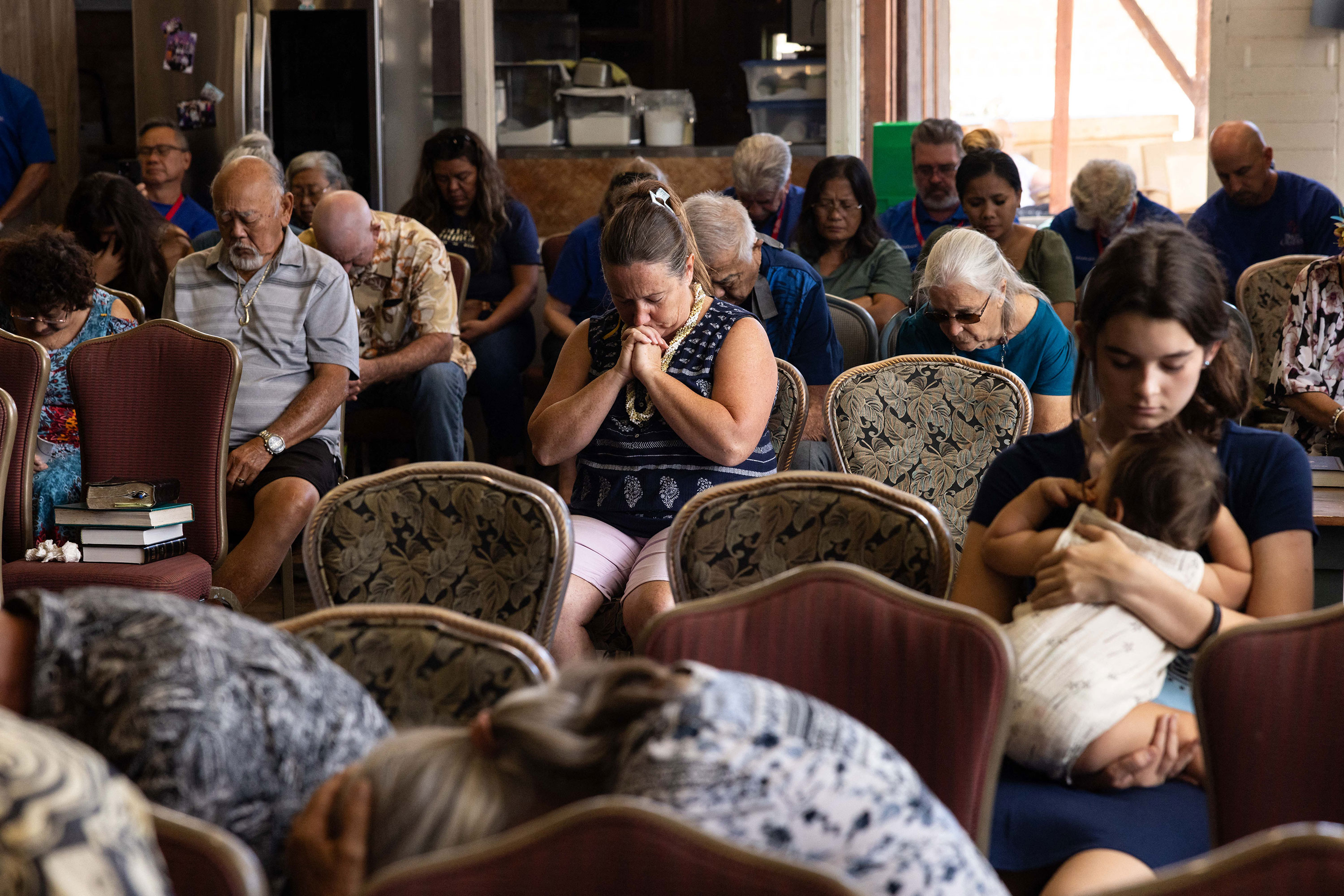 Churchgoers pray during a service held by Pastor Brown of Lahaina's Grace Baptist Church at Maui Coffee Attic in Wailuku on Sunday.