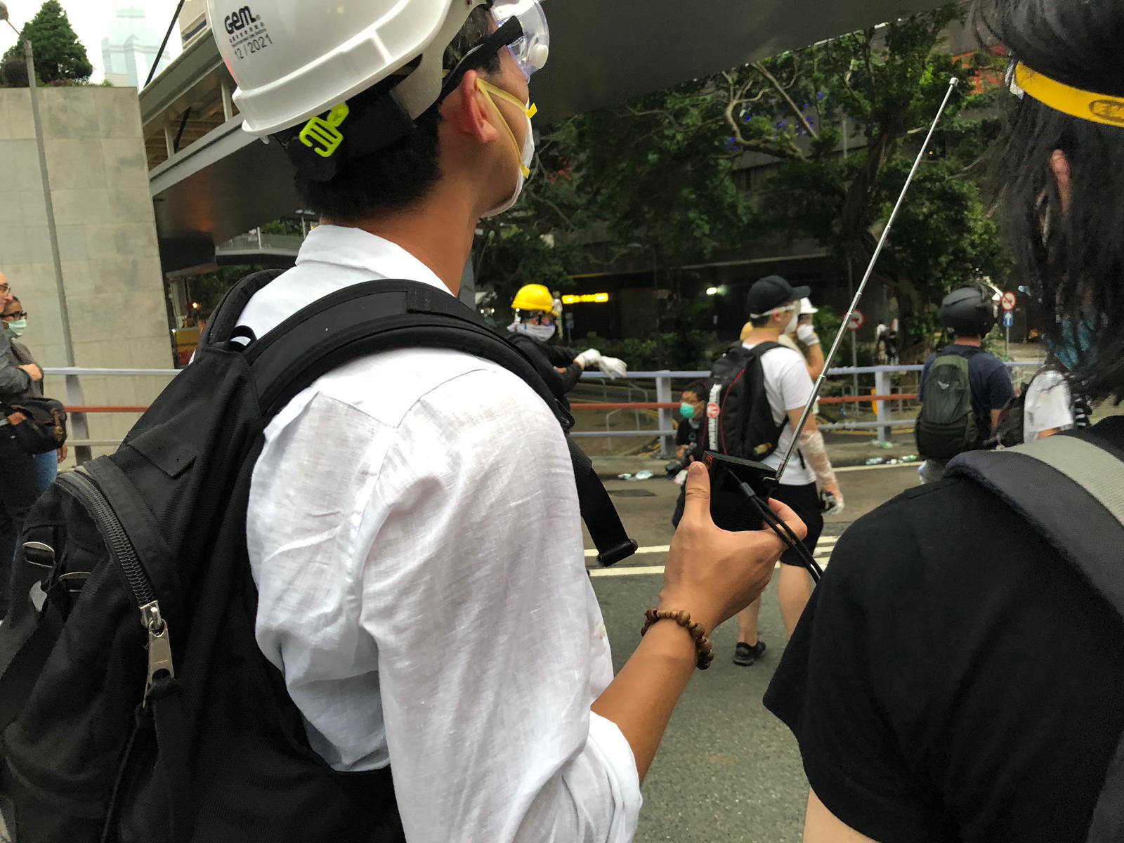 Protester with handheld radio for live updates.