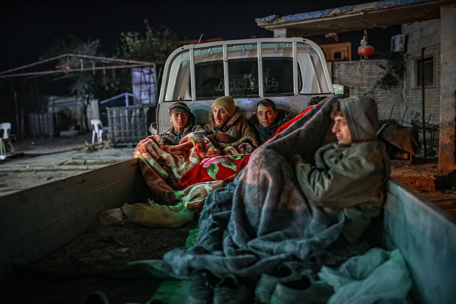 People spend the night in a vehicle after their house was damaged or collapsed in Aleppo, Syria, on February 8. 