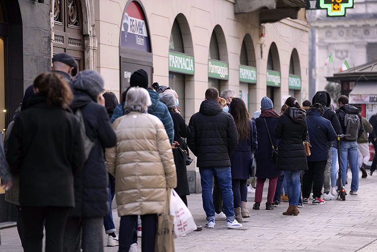 People line up at a pharmacy to book nasal swabs tests, in Milan, Italy on Wednesday, Dec. 22, 2021.