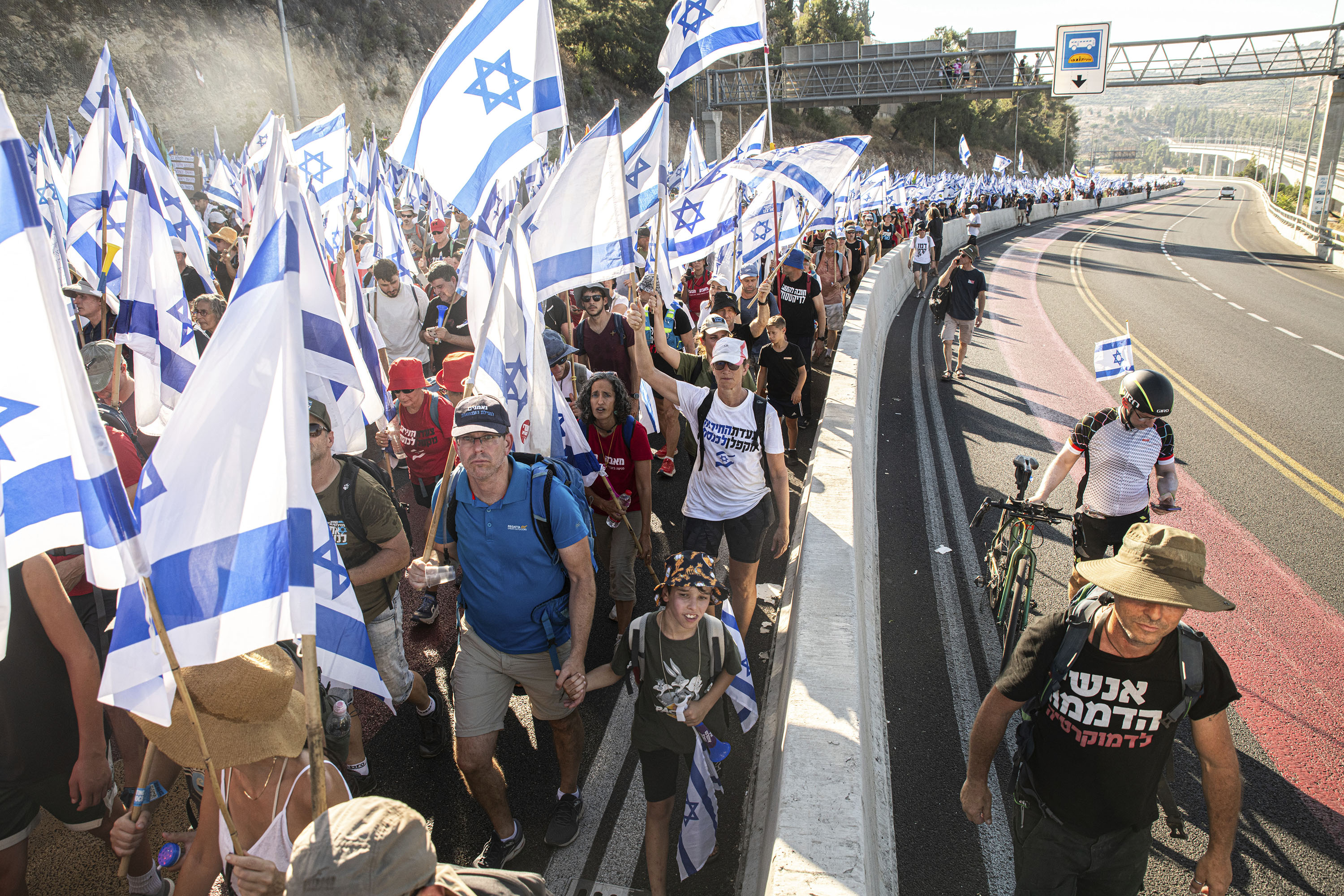 Protestors against the reform wave the Israeli flag as they climb the entrance road to Jerusalem on July 22.
