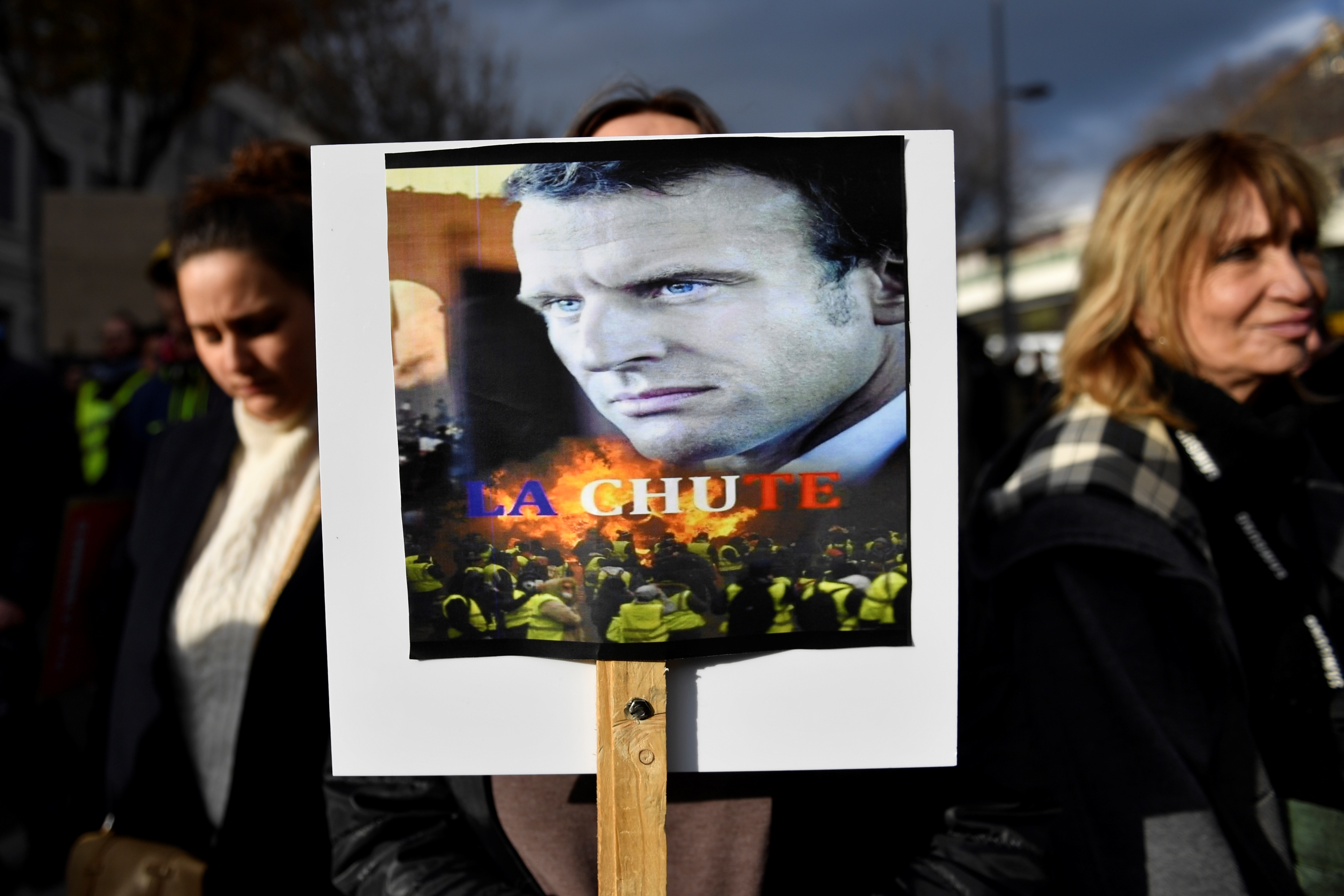 A woman in Marseille holds a placard picturing Macron with the word "the fall." Photo: Clement Mahoudeau/AFP/Getty Images