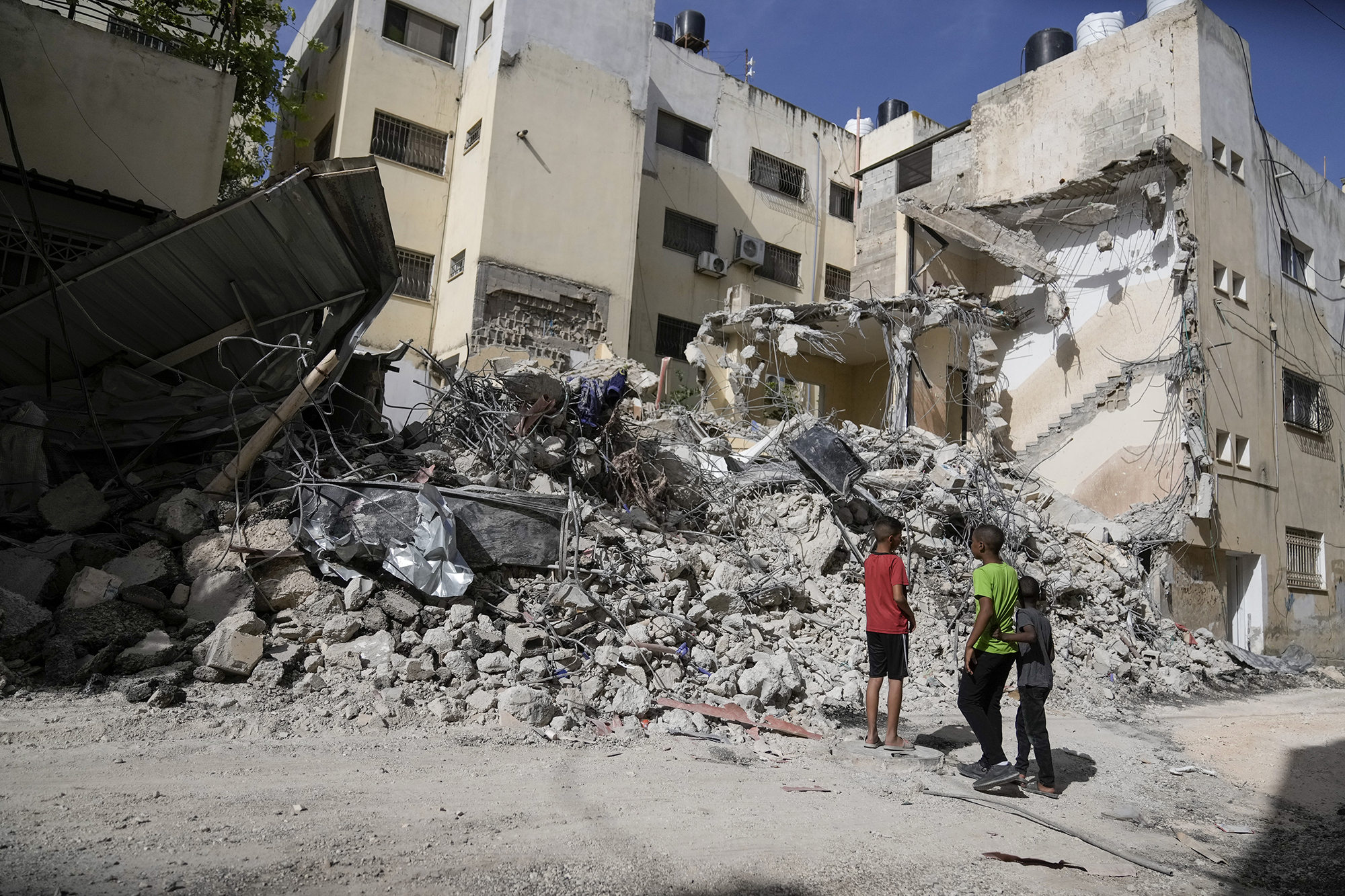 Palestinian children look at a damaged building after Israeli forces raided the West Bank city of Jenin, on May 23.