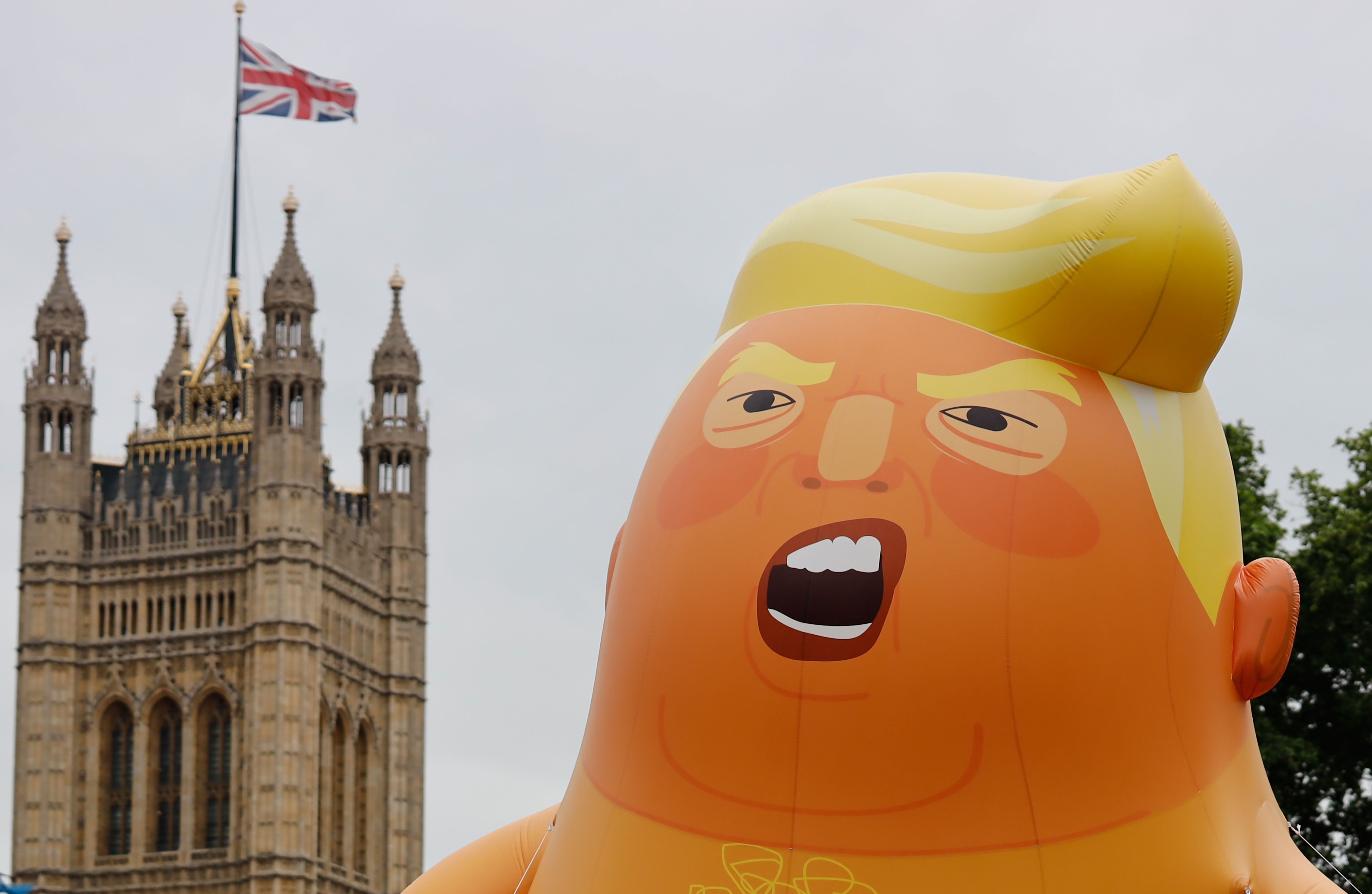 A giant balloon depicting US President Donald Trump as an orange baby floats above anti-Trump demonstrators in Parliament Square, London, on June 4, 2019 -- the second day of Trump's three-day state visit to the UK.