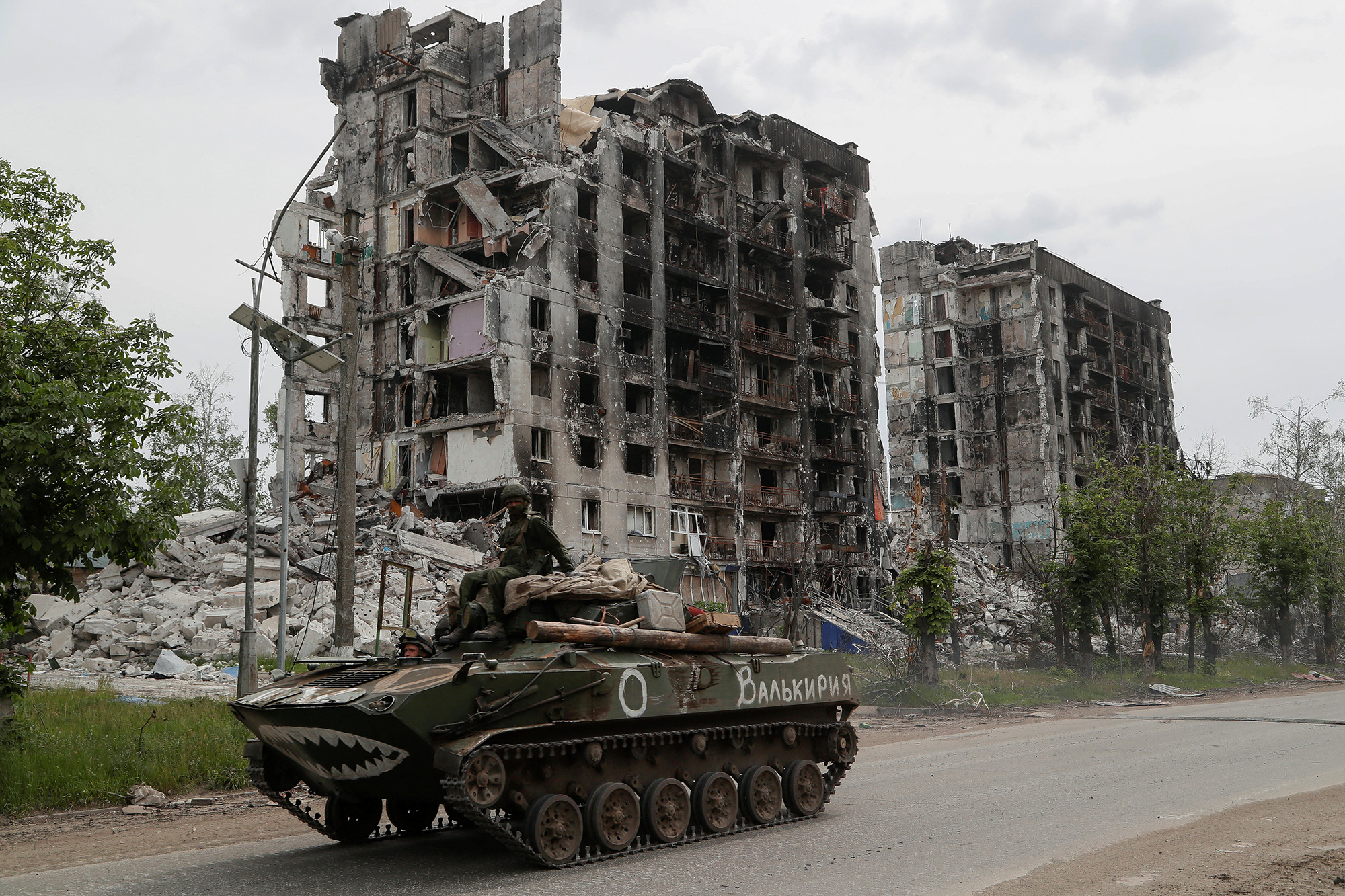 Pro-Russian troops drive an armored vehicle past destroyed residential buildings in the town of Popasna in Luhansk region, Ukraine, on May 26.