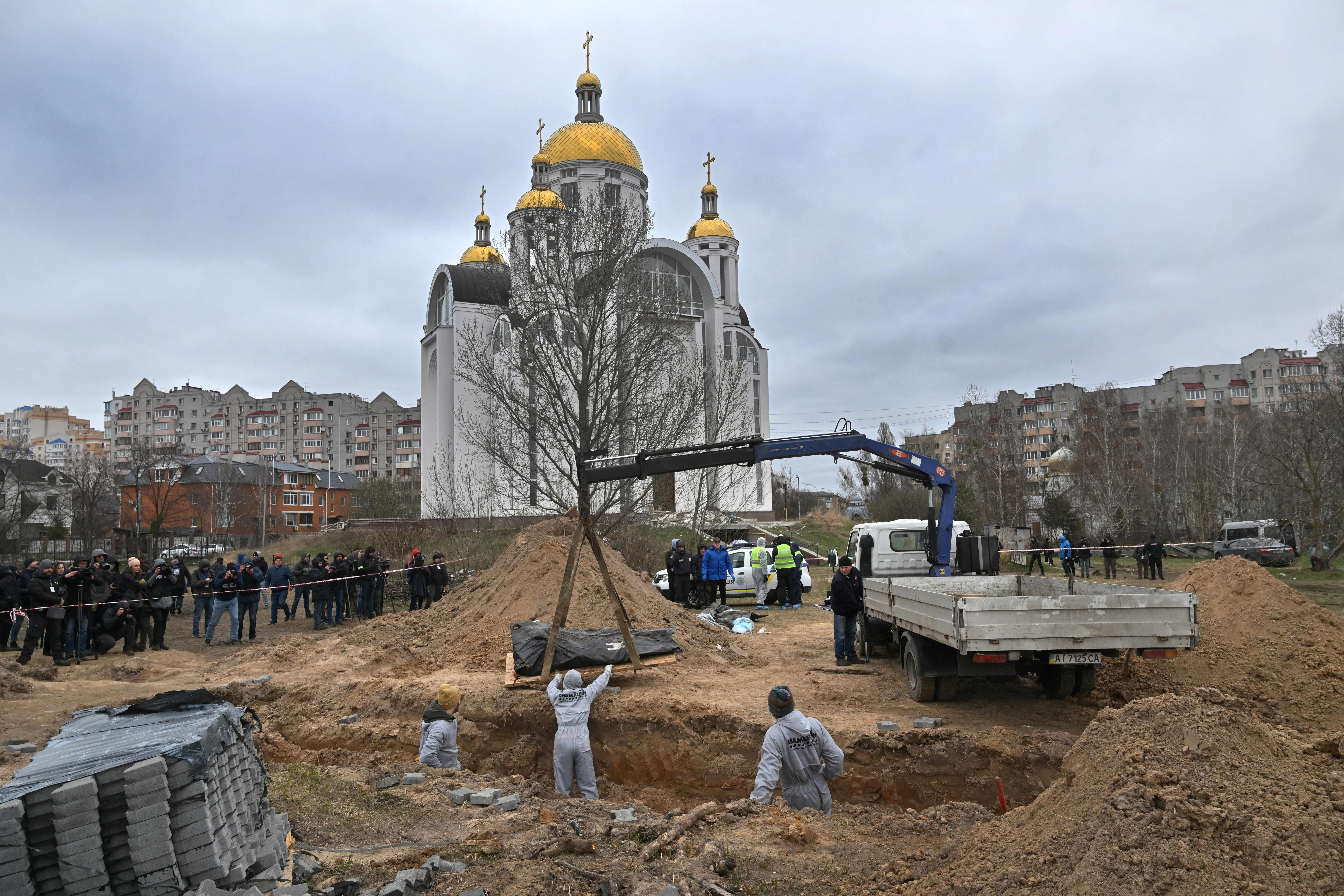 Journalists document as bodies are exhumed from a mass grave on the grounds of the Church of St. Andrew and Pyervozvannoho All Saints in the Ukrainian town of Bucha, outside of Kyiv on April 13. 