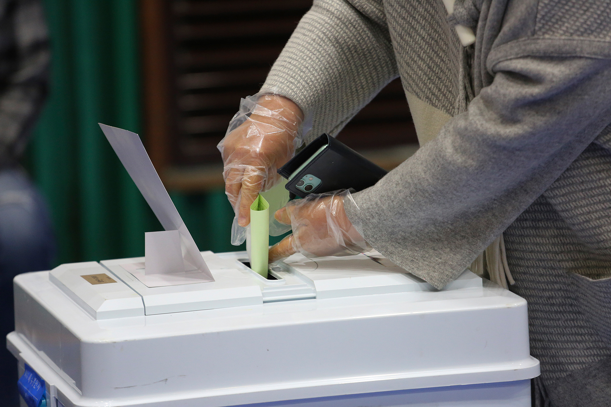 A voter wearing plastic gloves to help protect against the spread of the coronavirus casts a vote for the parliamentary election at a polling station in Seoul, South Korea, on Wednesday, April 15. 