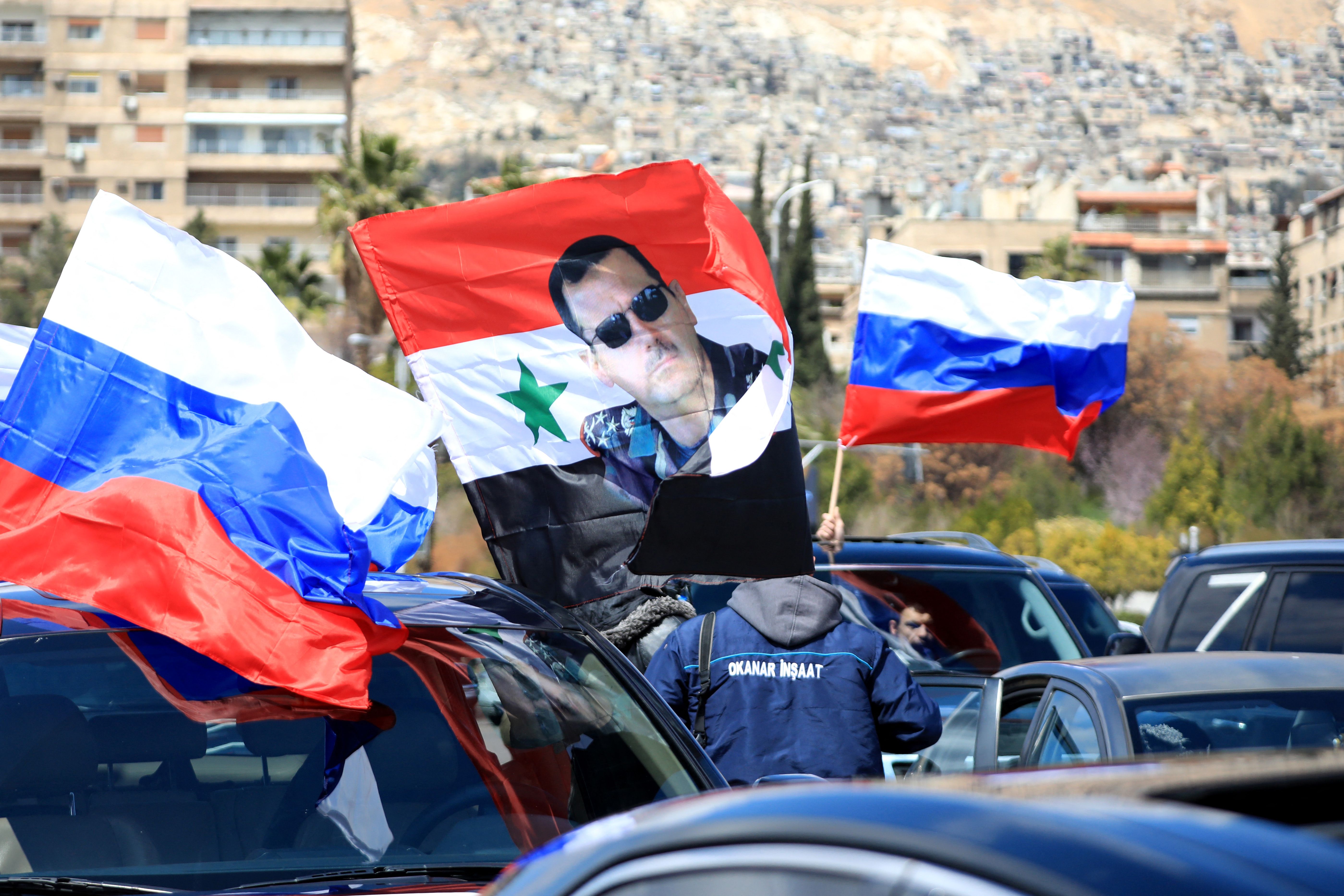 Syrians wave the Russian flag and a portrait of President Bashar al-Assad, during a rally in support of Russia in the Syrian capital Damascus, on March 25.